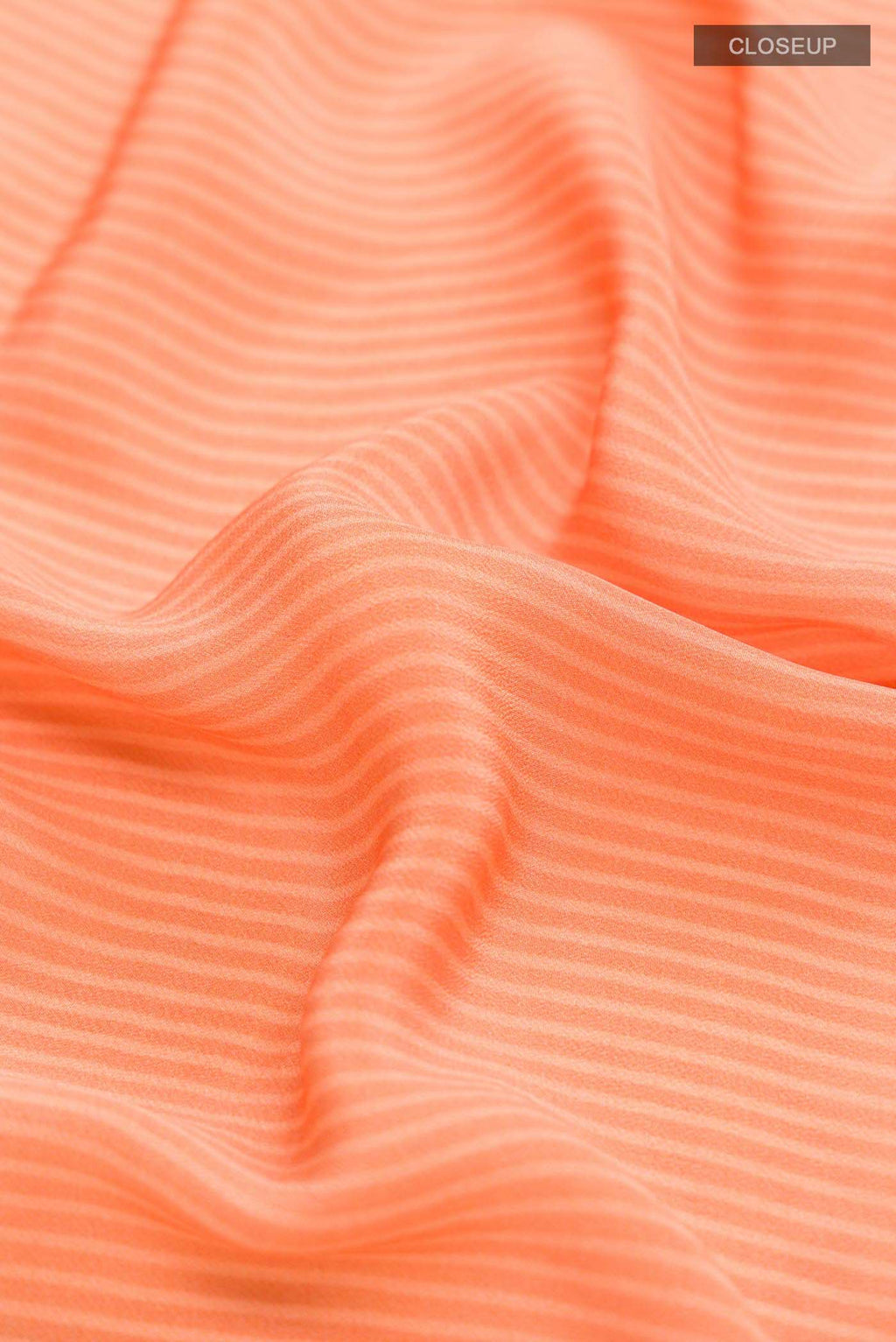 Close up of Orange Mysore Crepe Saree with Stripes on the body and Printed Border displaying folds