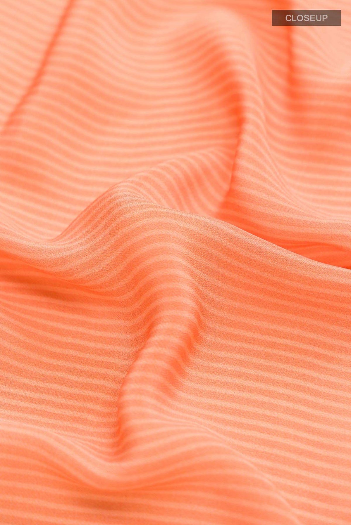 Close up of Orange Mysore Crepe Saree with Stripes on the body and Printed Border displaying folds