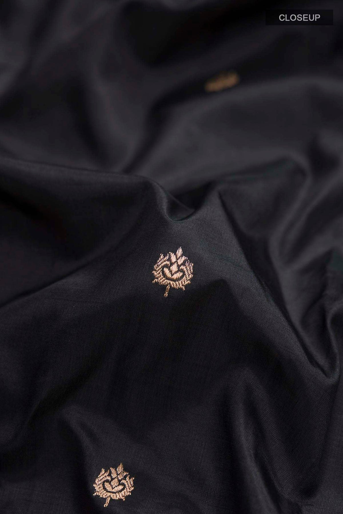 Close up of Black Banarasi Katan Silk Saree with Zari Butta on the body and Zari Border displaying folds