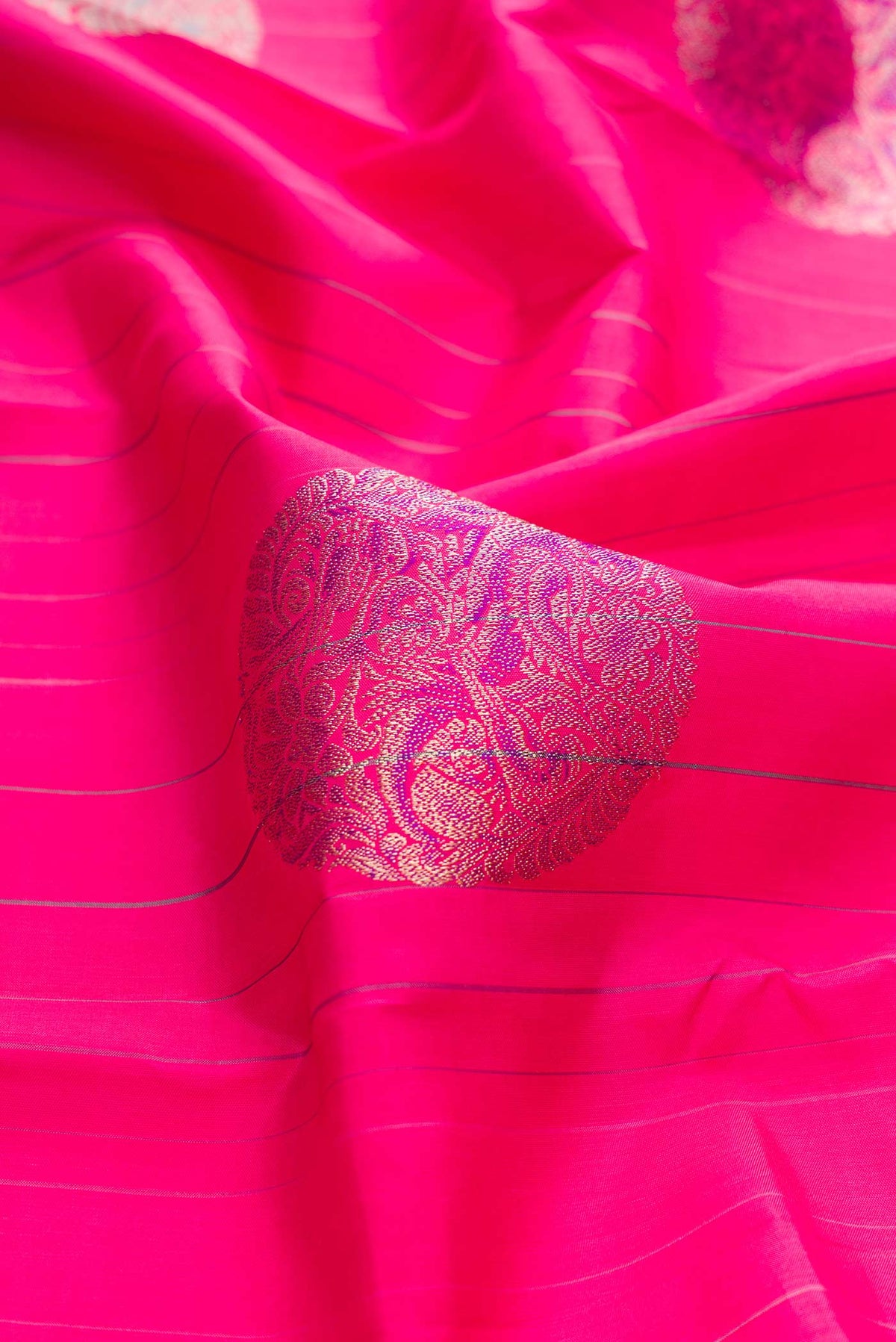 Close up of Dark Pink Dual Tone Kanchipuram Silk Saree with Zari And Thread Butta on the body and Without Border displaying folds