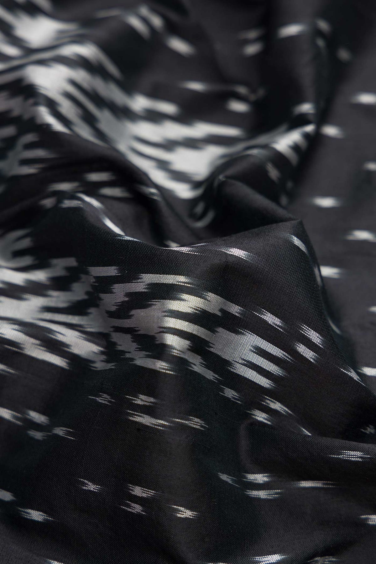 Close up of Black Dual Tone Double Ikat Saree with Ikat Print on the body and Ikat Border.  displaying folds