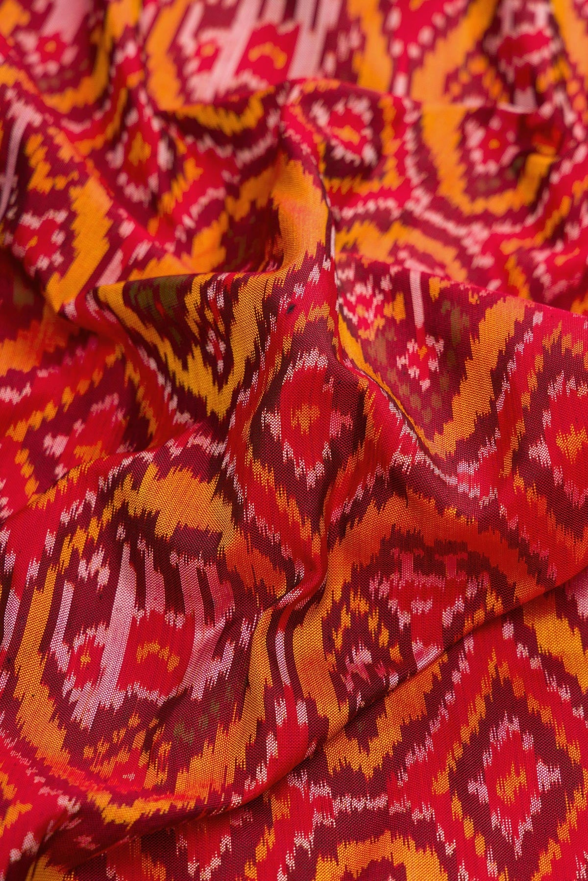 Close up of Red Dual Tone Double Ikat Saree with Ikat Print on the body and Zari Border.  displaying folds