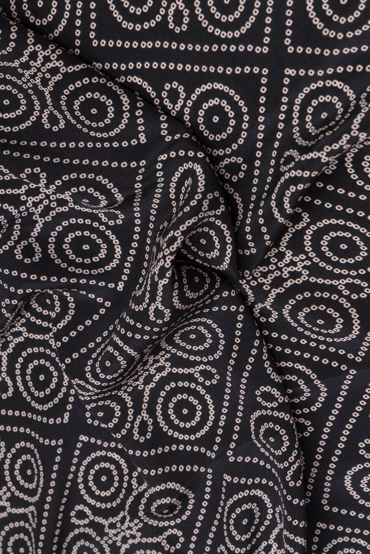Close up of Black Crepe Saree with Bandhani Print on the body and Printed Border.  displaying folds