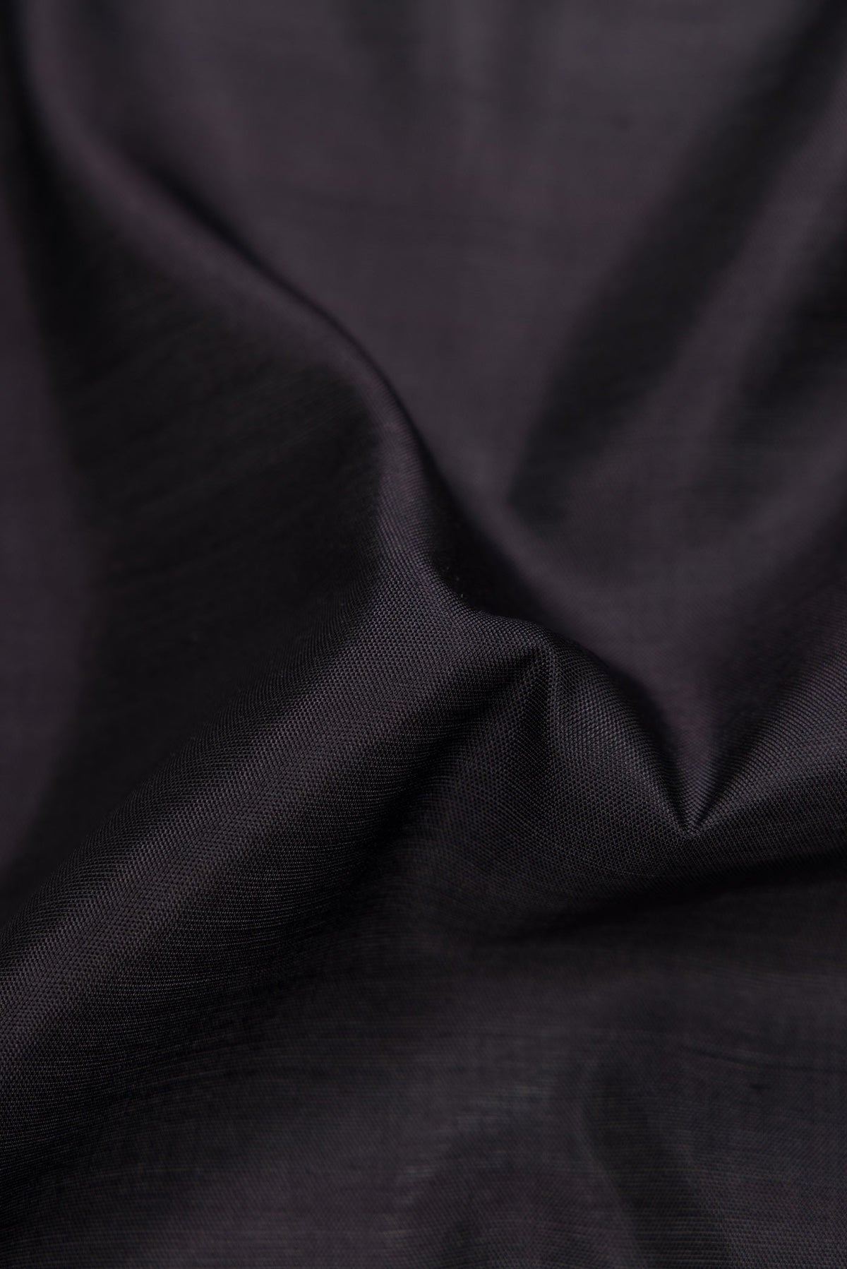 Close up of Black Dual Tone Rajkot Patola Silk Saree with Plain Body and Ikat Border displaying folds