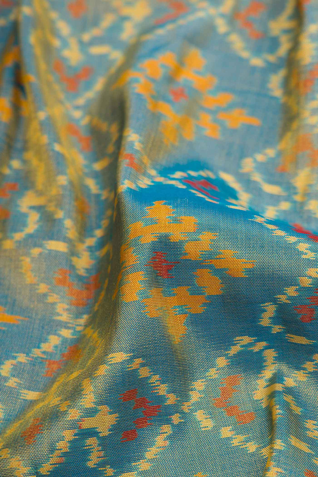 Close up of Light Blue Dual Tone Rajkot Patola Silk Saree with Ikat Print on the body and Zari Border displaying folds