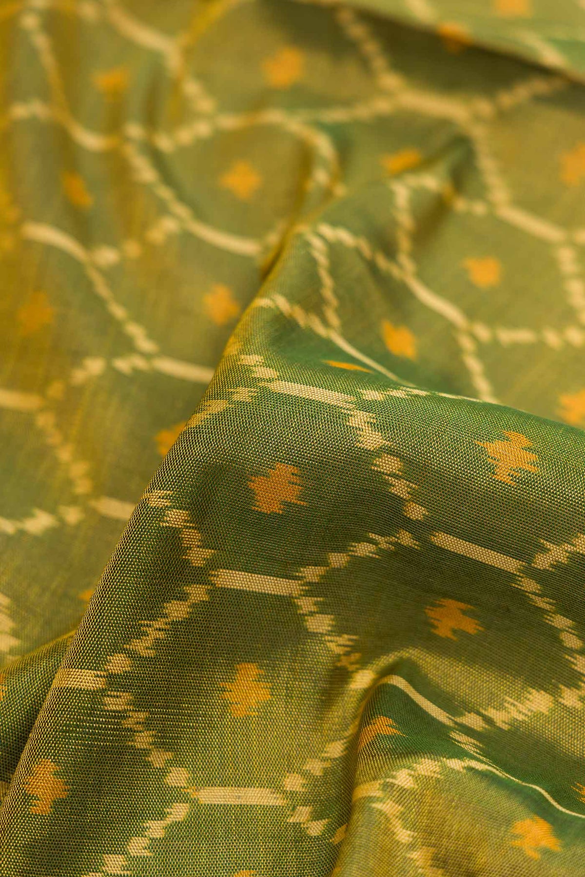 Close up of Mehandi Green Dual Tone Rajkot Patola Silk Saree with Ikat Print on the body and Ikat Border displaying folds