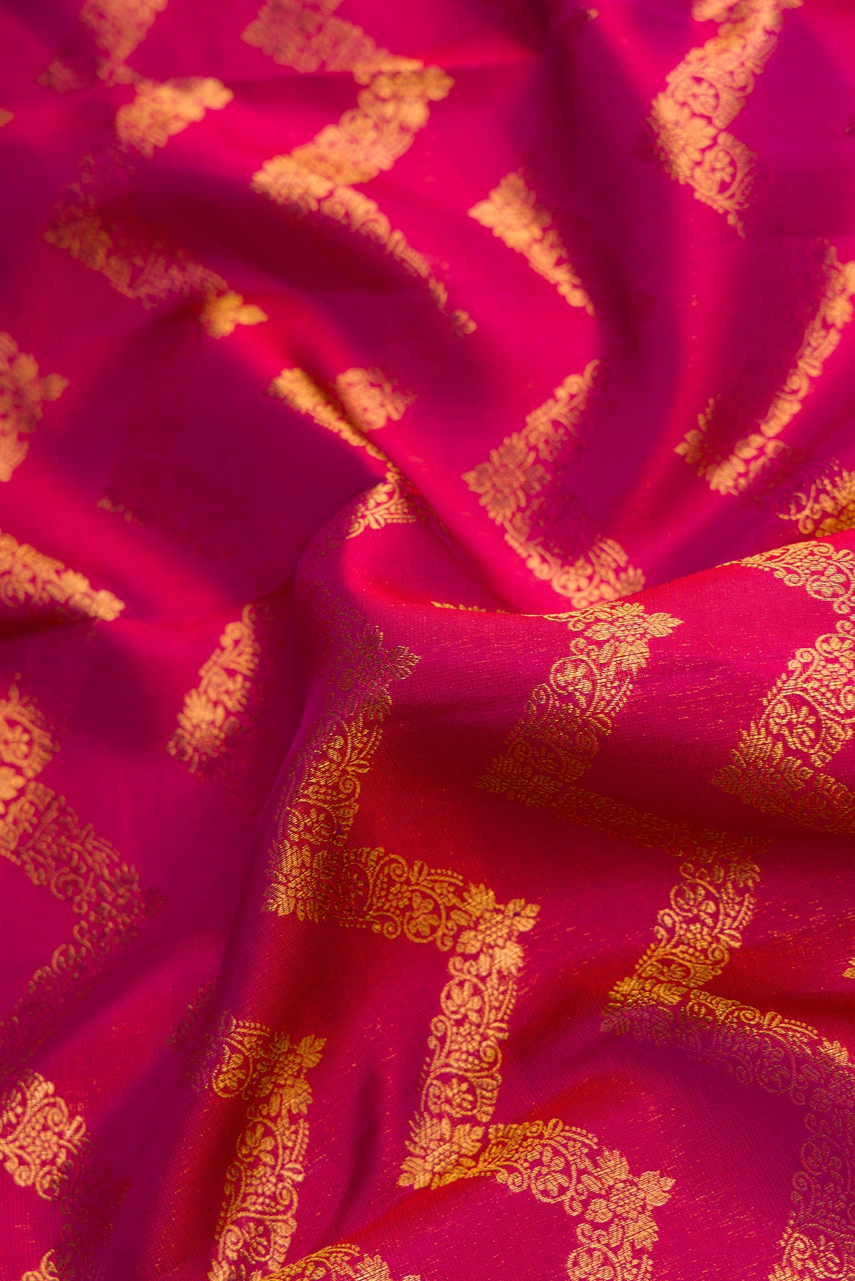 Close up of Magenta Kanchipuram Silk Saree with Zari Brocade on the body and Zari Border.  displaying folds