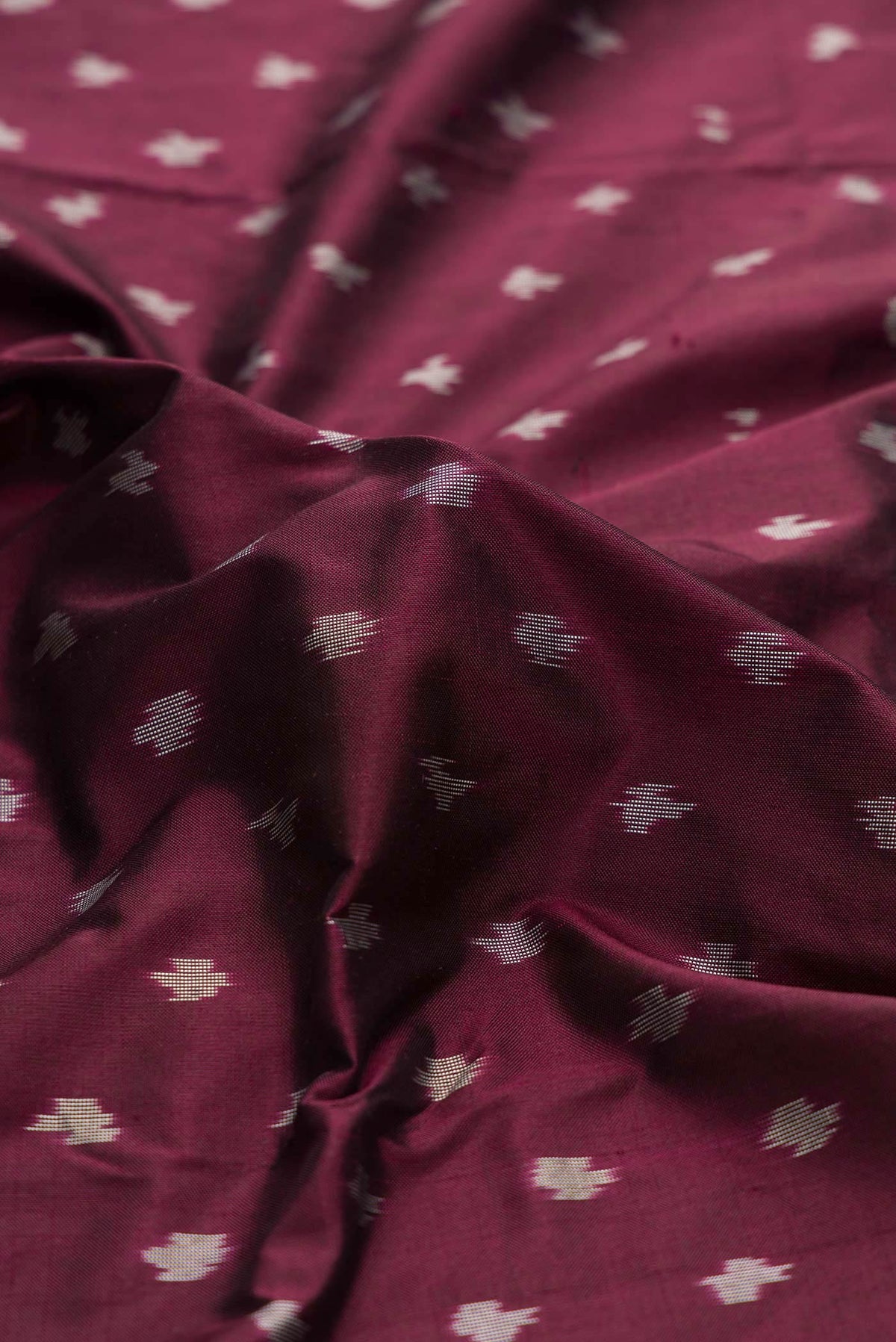 Close up of Burgundy Dual Tone Double Ikat Saree with Ikat Print on the body and Ikat Border displaying folds