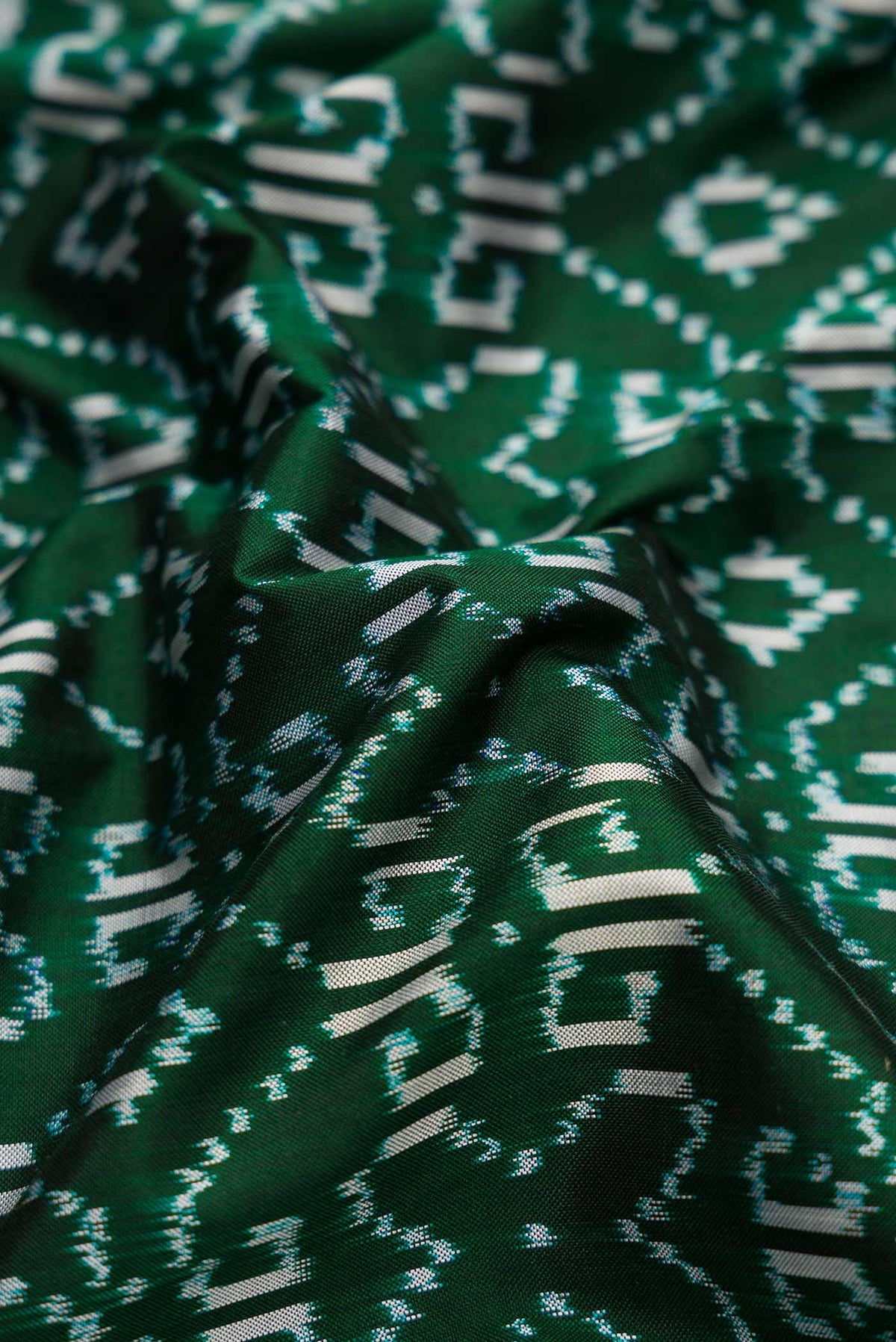 Close up of Green Dual Tone Double Ikat Saree with Ikat Print on the body and Zari Border.  displaying folds
