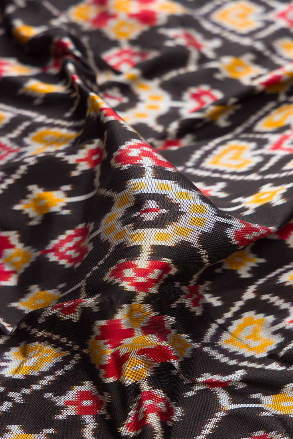 Close up of Black Dual Tone Double Ikat Saree with Ikat Print on the body and Ikat Border displaying folds