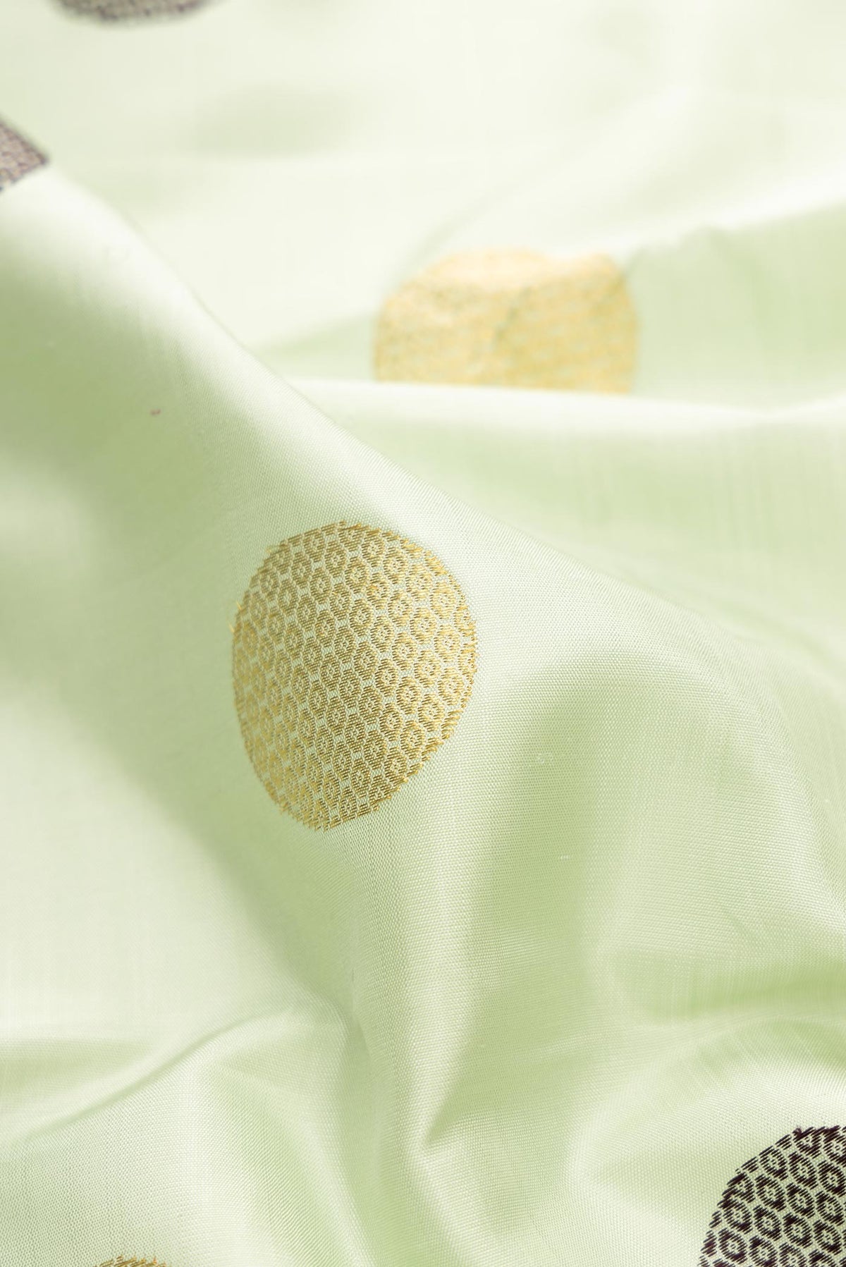 Close up of Pure Silk Pure Zari Pista Green Dual Tone Kanchipuram Saree with Zari And Thread Butta on the body and Zari And Thread Border displaying folds