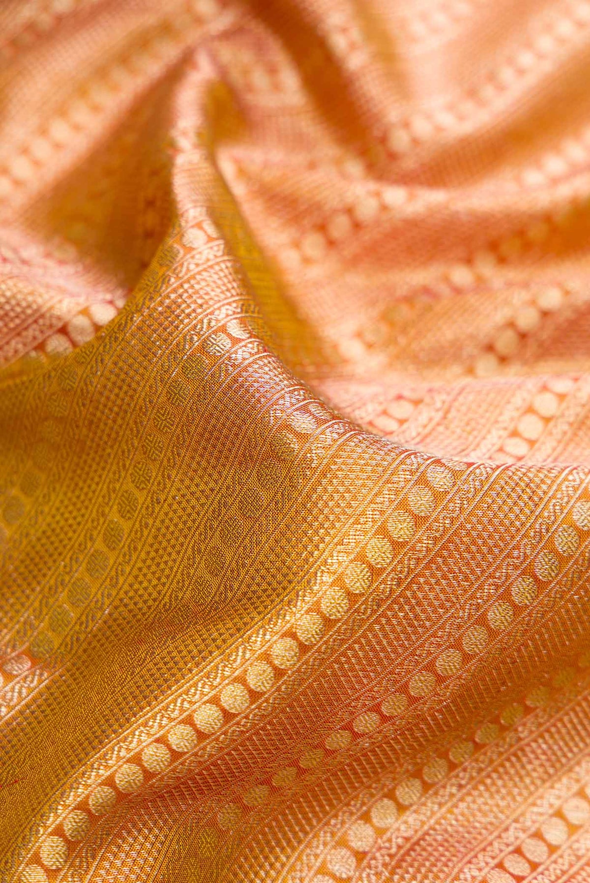 Close up of Gold Dual Tone Kanjivaram Tissue Silk Saree with Zari Brocade on the body and Fancy Border.  displaying folds