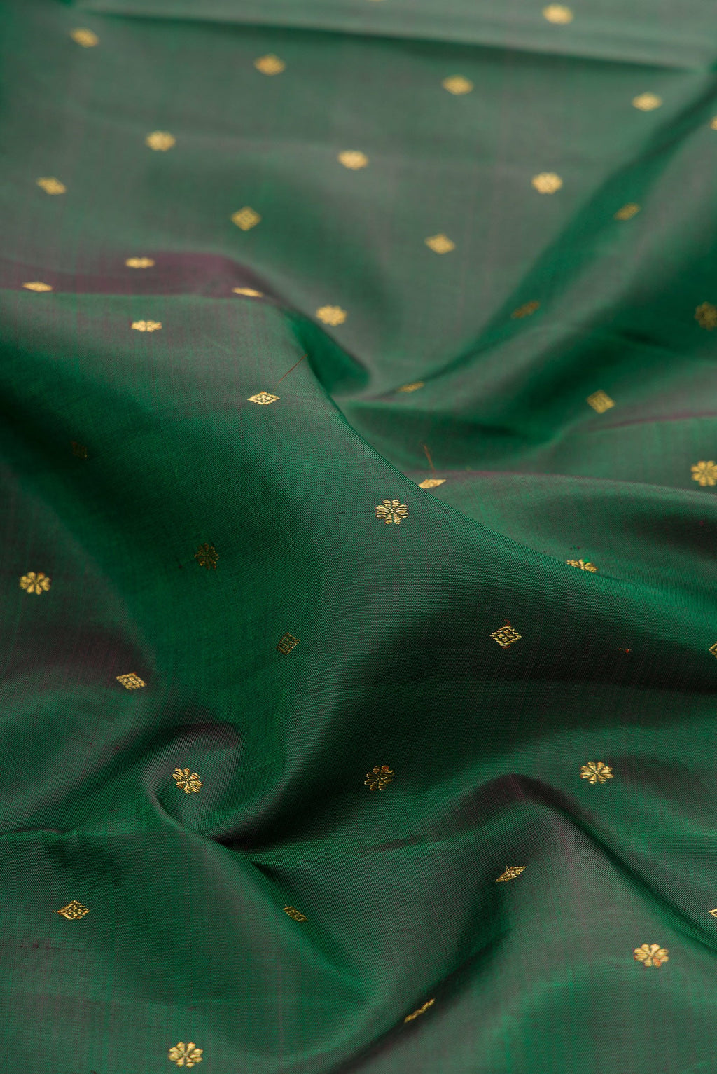 Close up of Pure Silk Pure Zari Green Dual Tone Kanjivaram Saree with Zari Butta on the body and Zari Border.  displaying folds