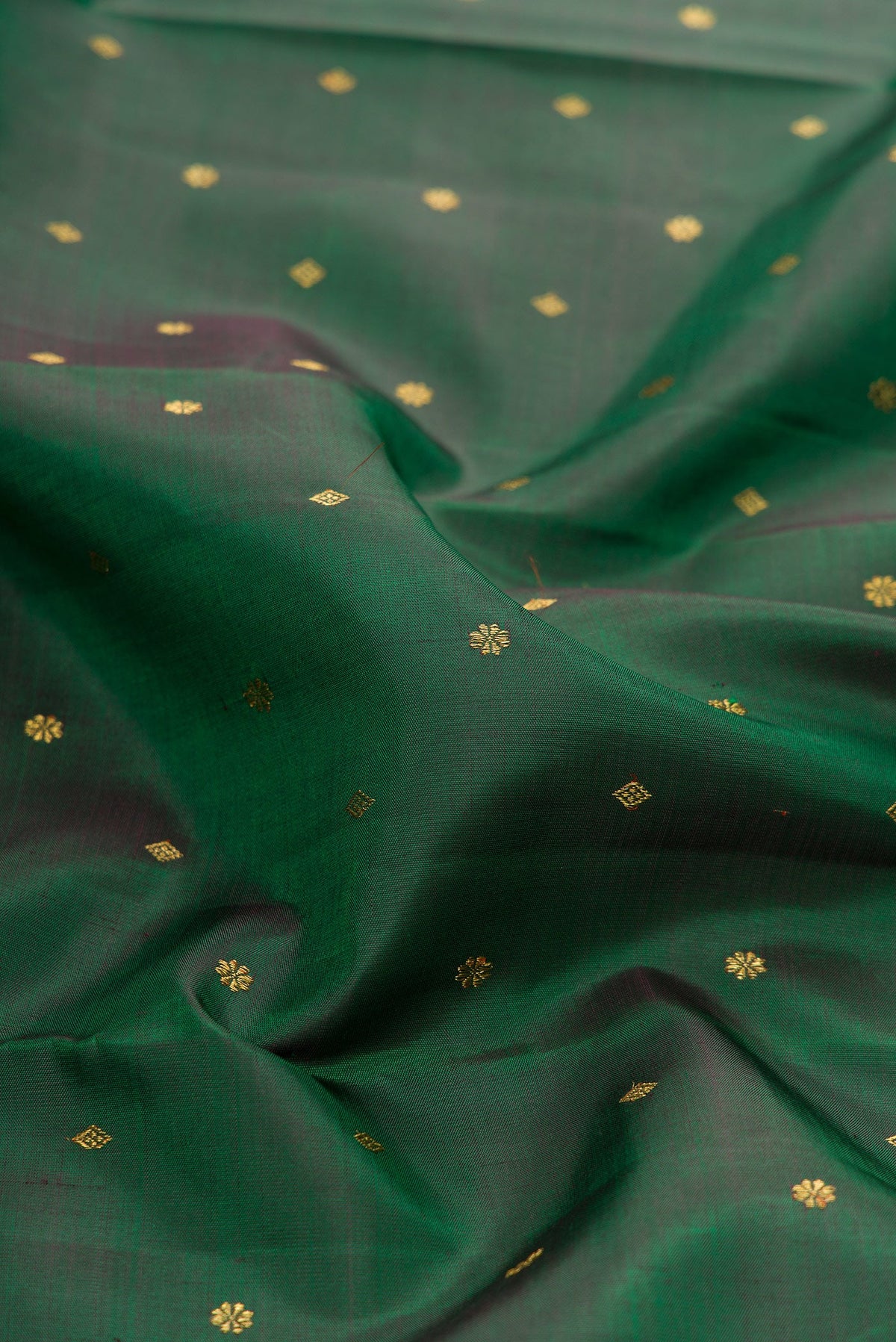 Close up of Pure Silk Pure Zari Green Dual Tone Kanjivaram Saree with Zari Butta on the body and Zari Border.  displaying folds