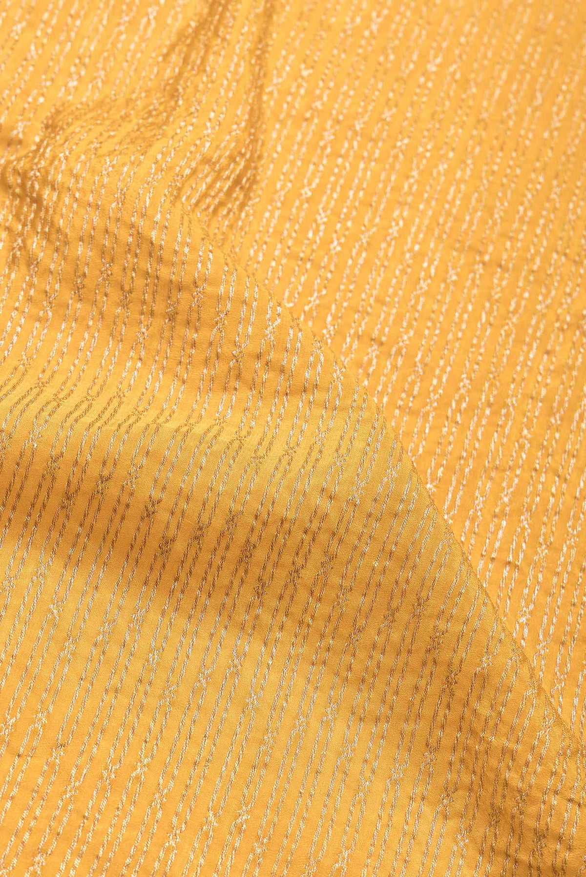 Close up of Mustard Dual Tone Banarasi Georgette Saree with Zari Brocade on the body and Zari Border.  displaying folds