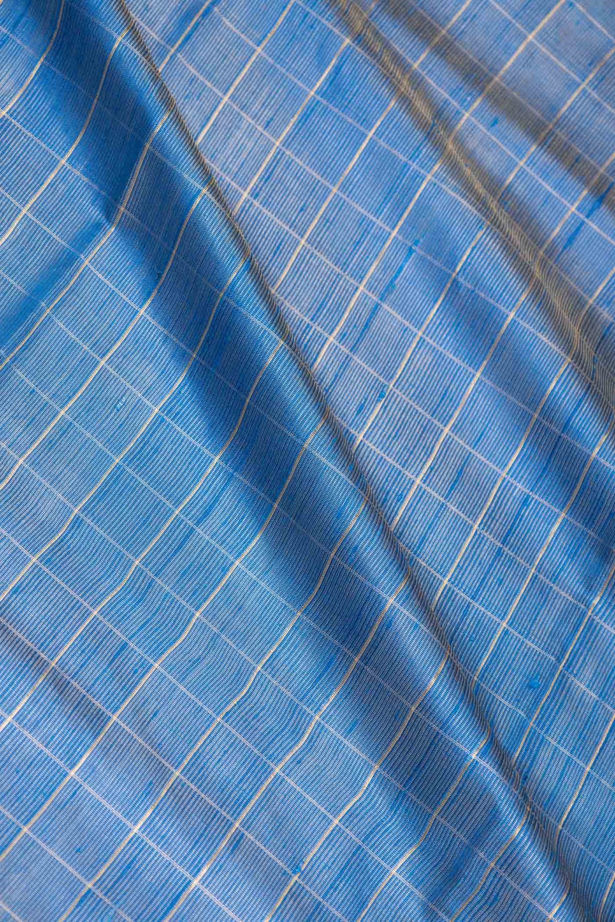 Close up of Sky Blue Dual Tone Tussar Saree with Checked design on the body and Fancy Border displaying folds