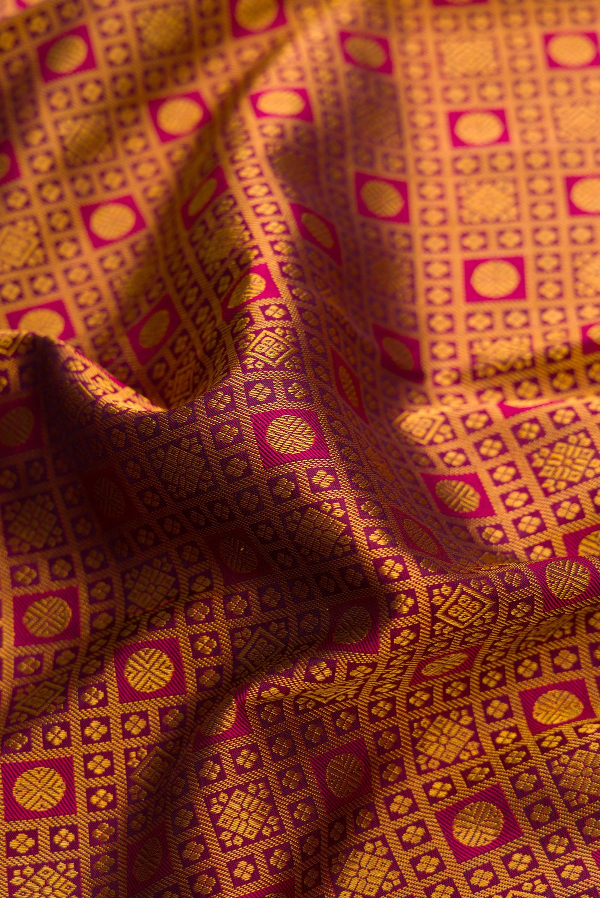 Close up of Magenta Kanjivaram Silk Saree with Zari Brocade on the body and Fancy Border.  displaying folds
