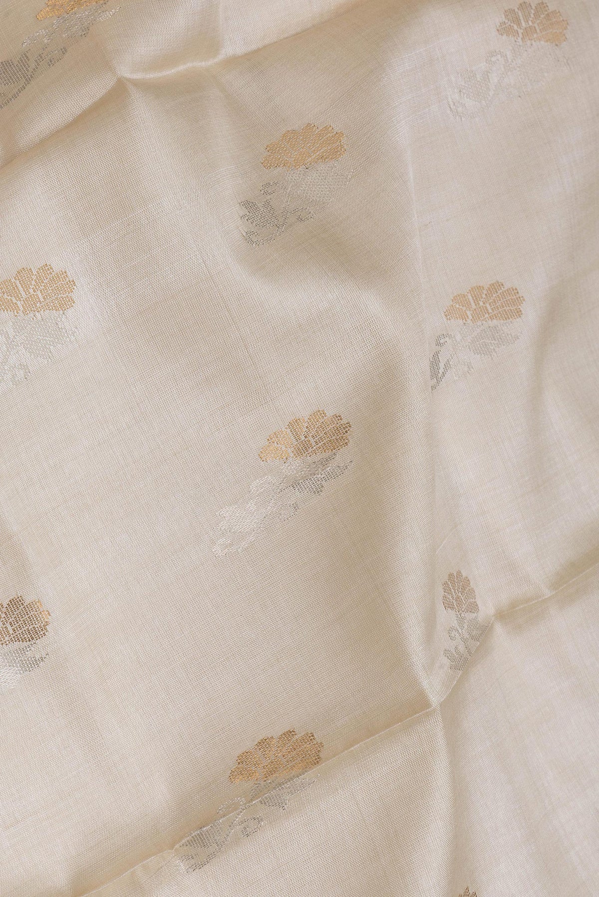 Close up of Beige Dual Tone Tussar Silk Saree with Zari Butta on the body and Without Border.  displaying folds