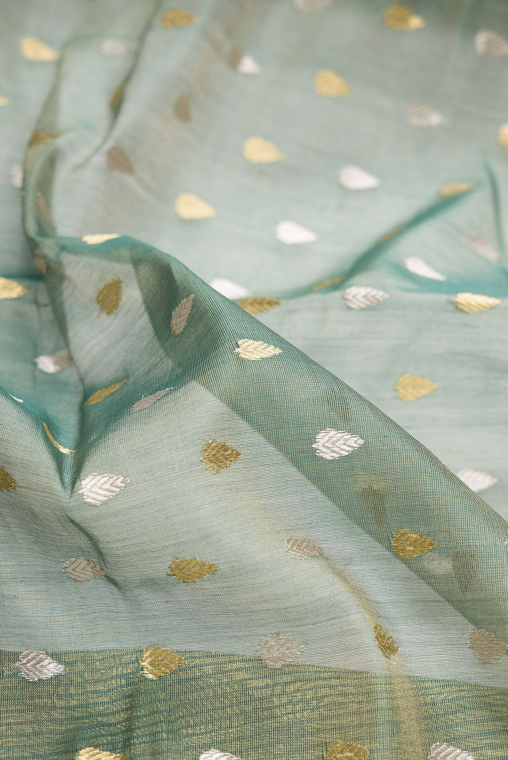 Close up of Green Dual Tone Chanderi Tissue Silk Saree with Zari Butta on the body and Zari Border.  displaying folds