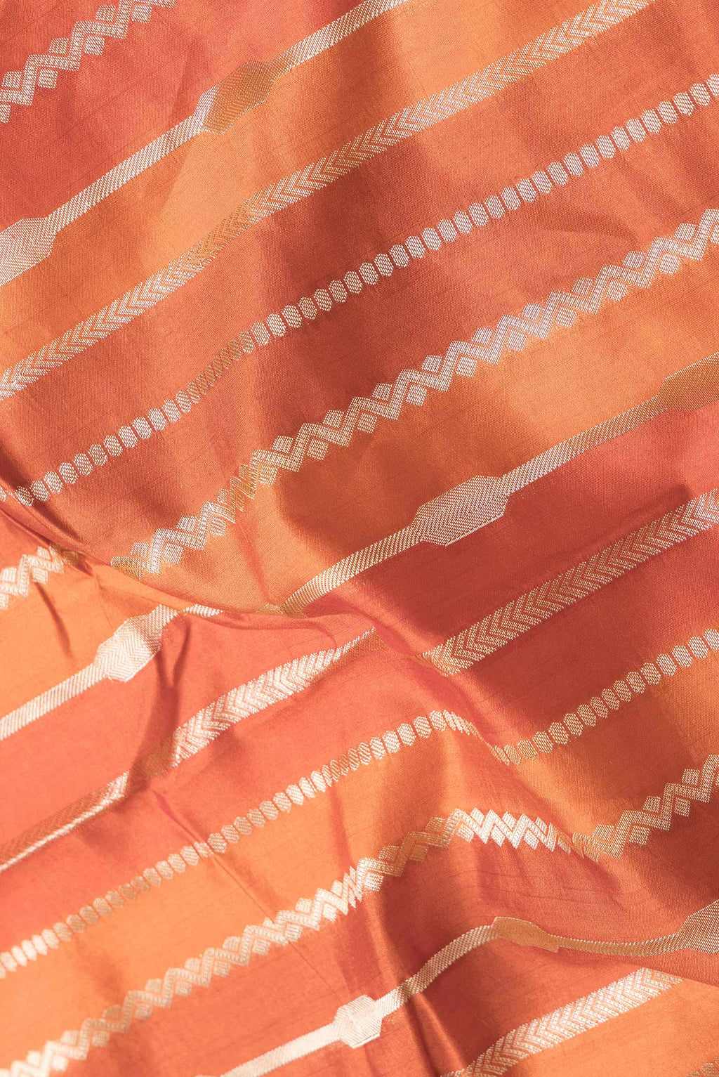 Close up of Orange Dual Tone Tussar Silk Saree with Stripes on the body and Zari Border.  displaying folds