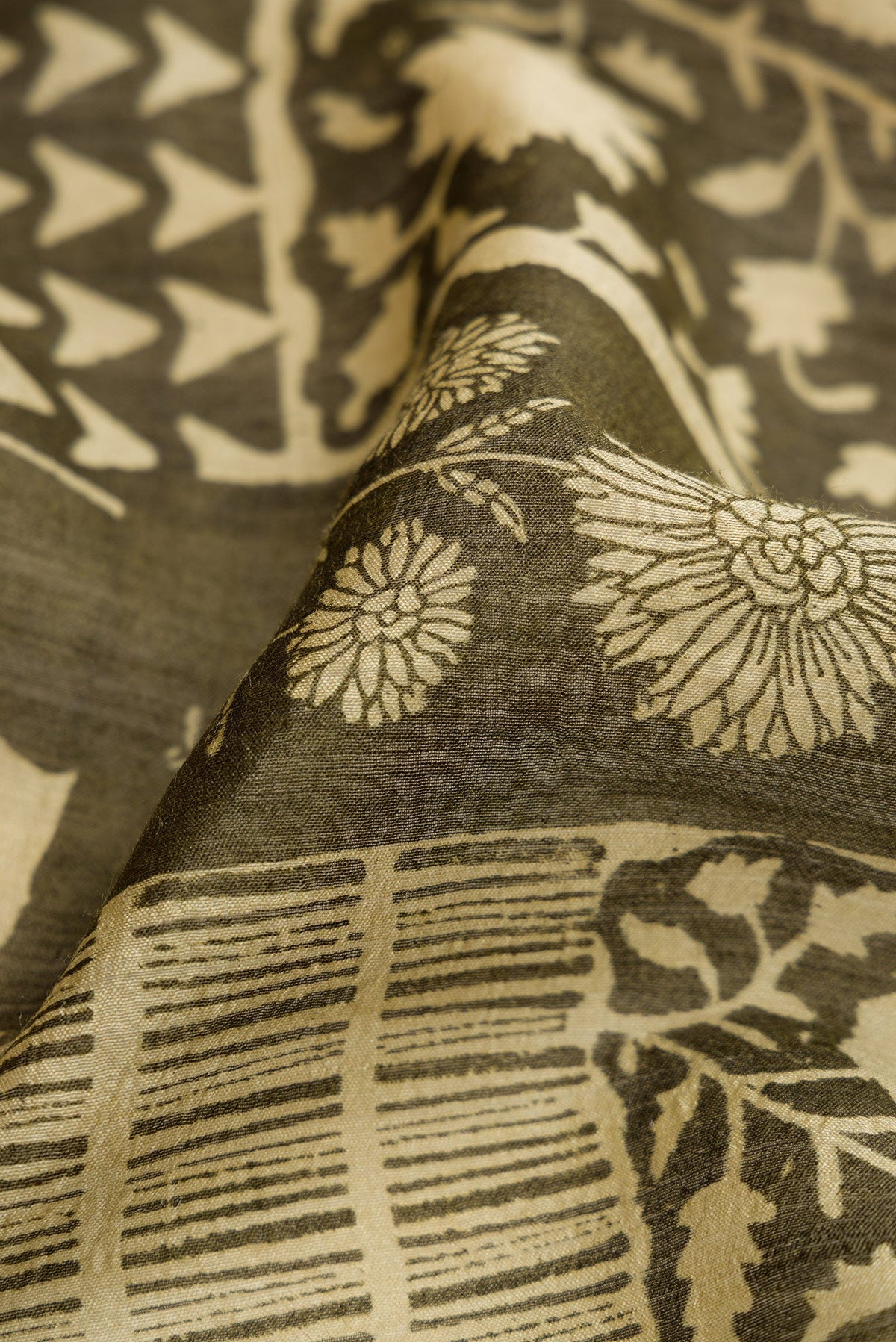 Close up of Mehandi Green Dual Tone Tussar Silk Saree with Printed design on the body and Zari Border.  displaying folds