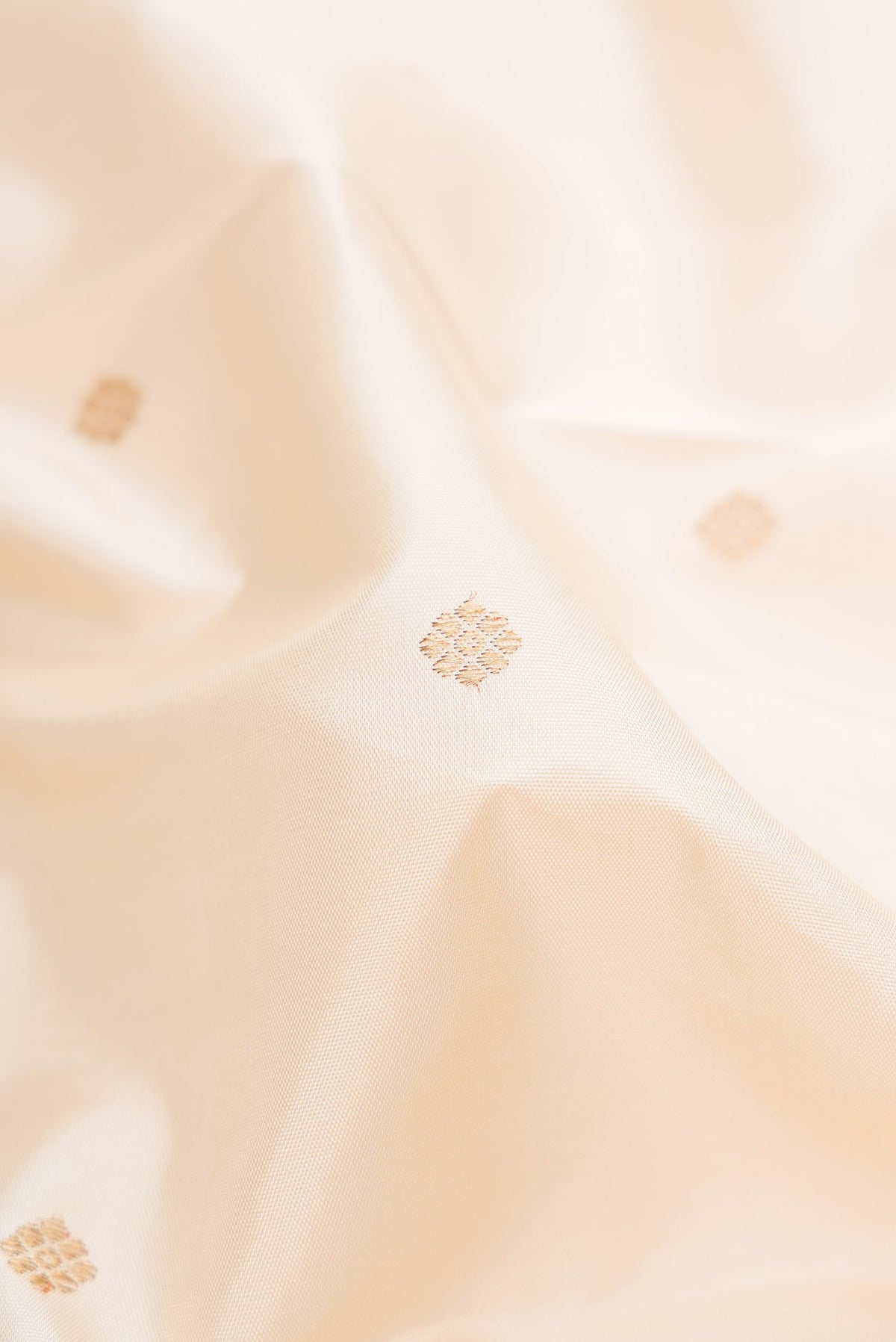 Close up of Pure Silk Pure Zari Cream Kanchipuram Saree with Zari Butta on the body and Temple Border.  displaying folds