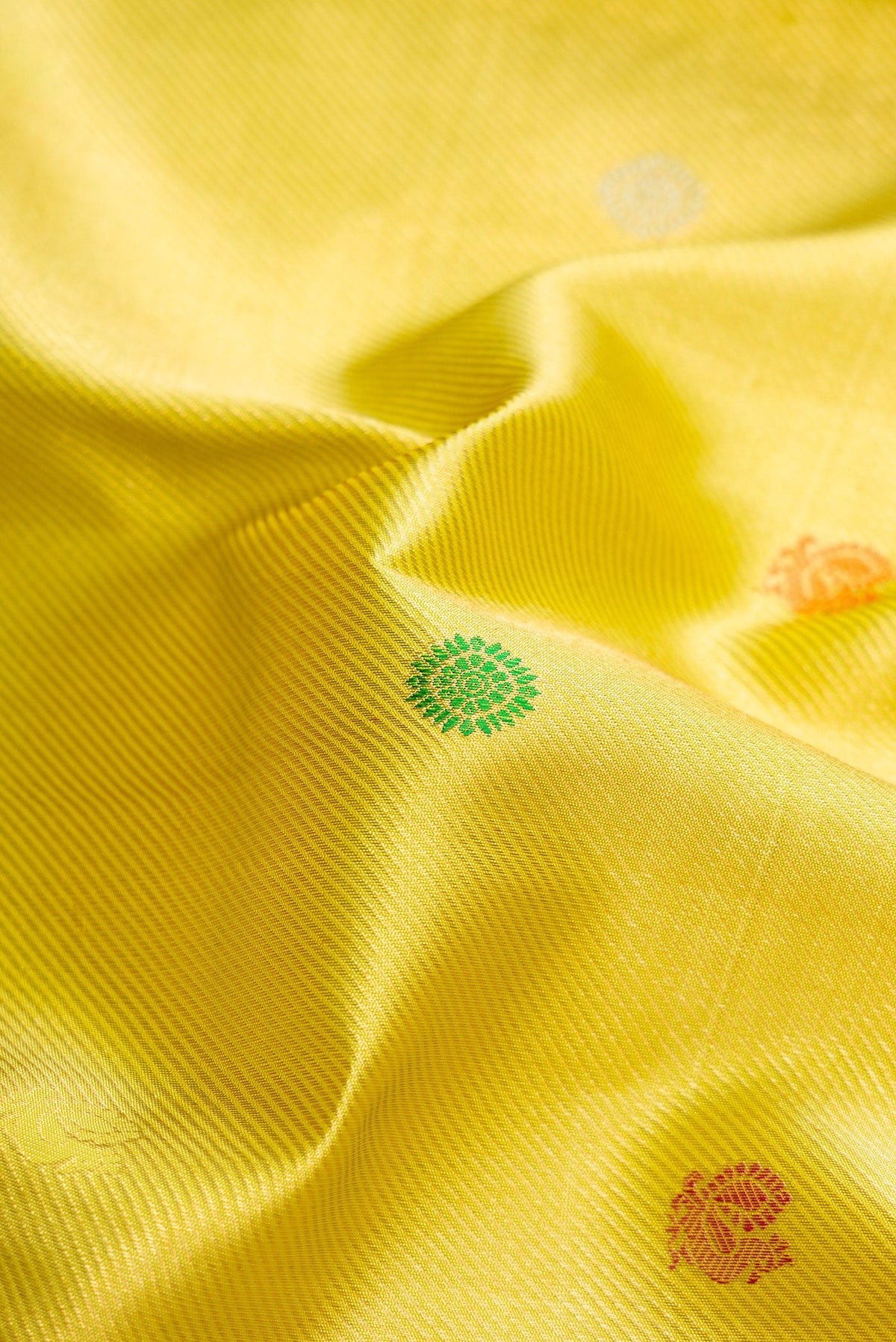 Close up of Lemon Yellow Dual Tone Kanchipuram Silk Saree with Zari Brocade on the body and Zari Border.  displaying folds