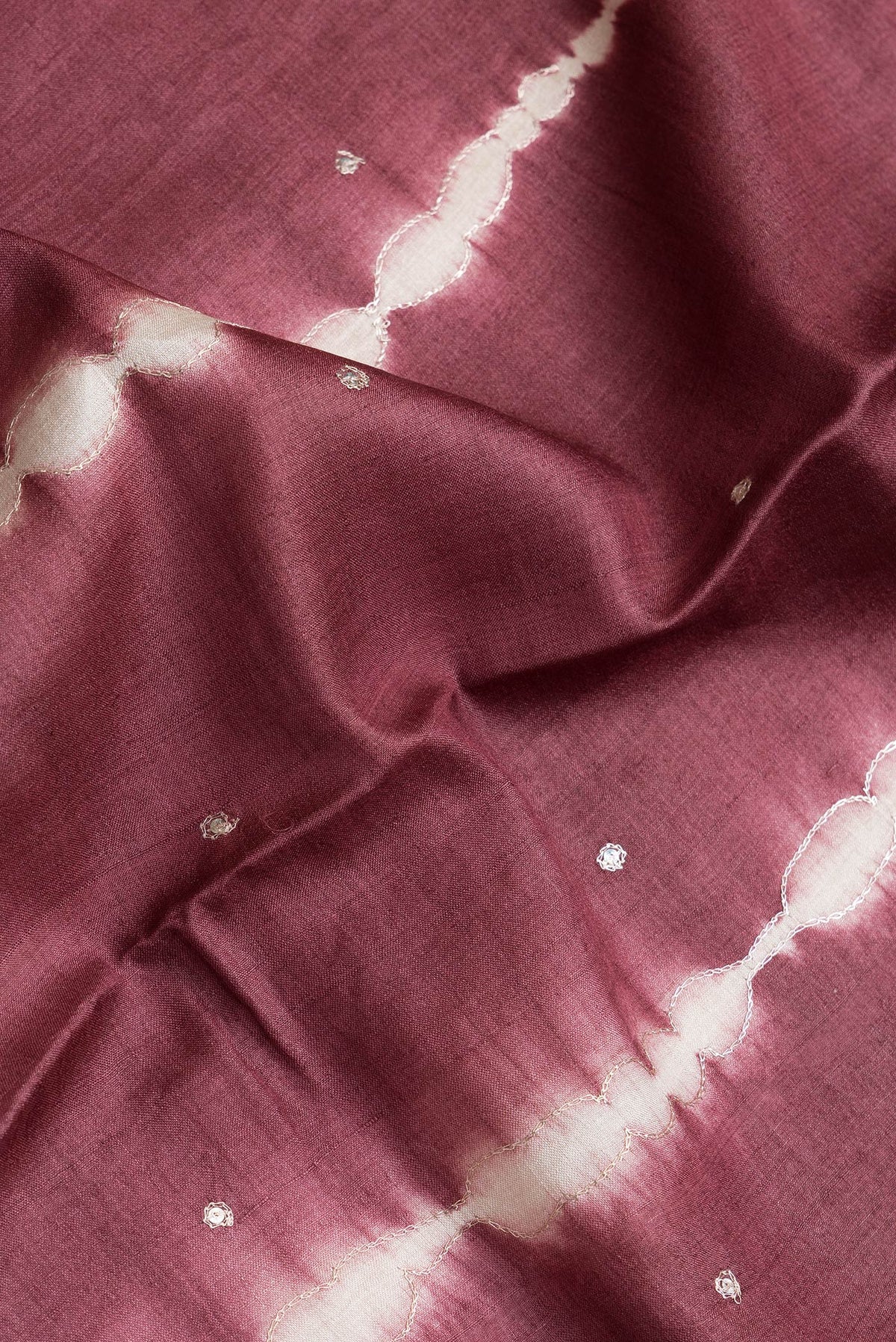 Close up of Maroon Dual Tone Tussar Silk Saree with Embroidery on the body and Without Border.  displaying folds