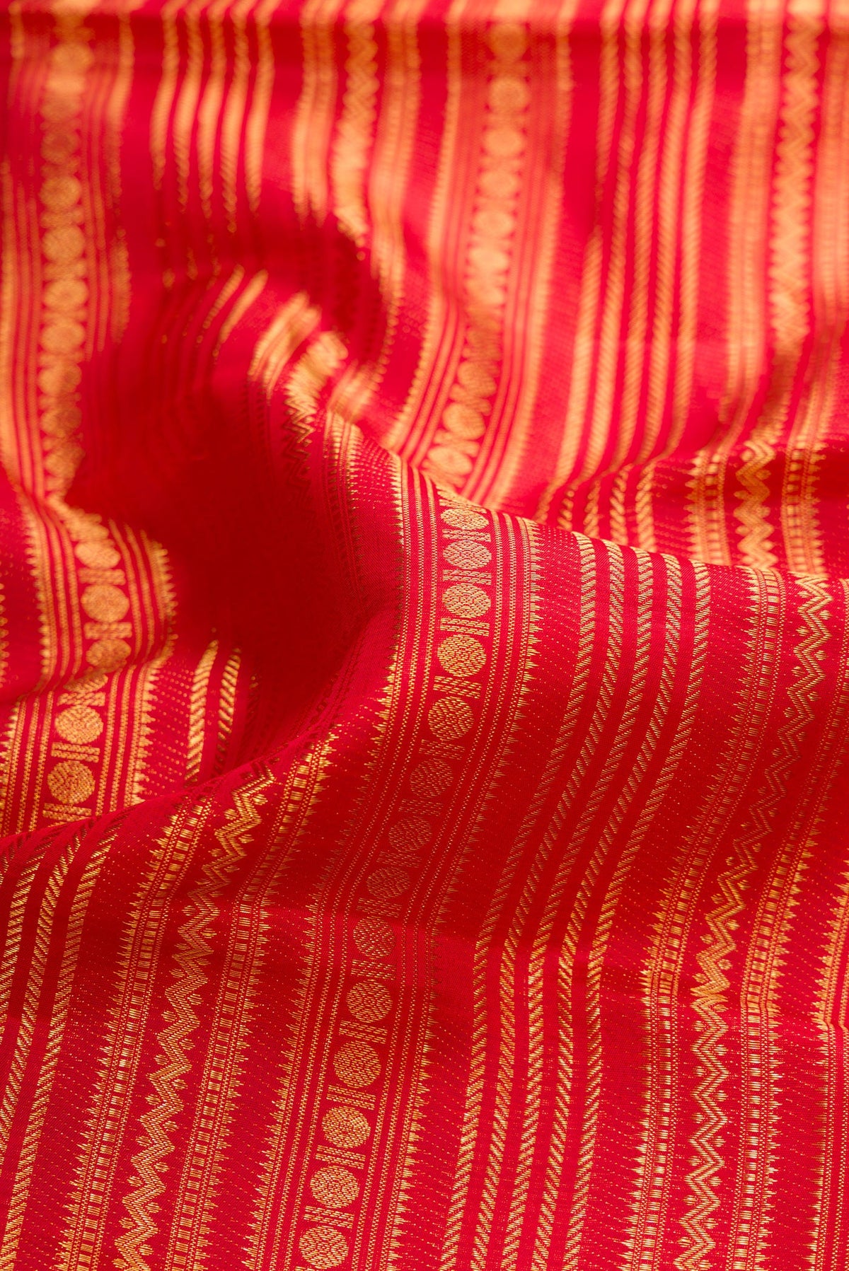 Close up of Red Dual Tone Kanchipuram Silk Saree with Zari Brocade on the body and Fancy Border.  displaying folds