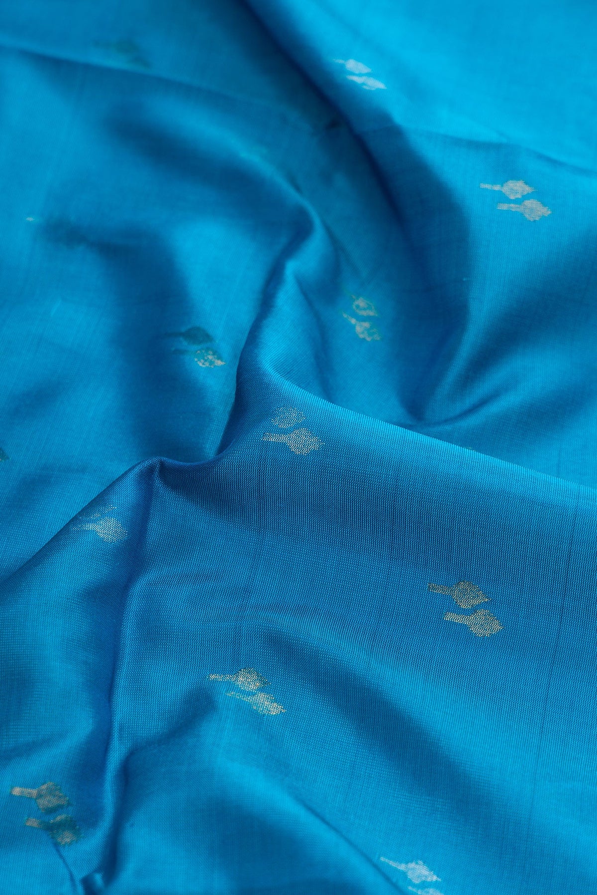 Close up of Sky Blue Dual Tone Soft Silk Saree with Zari Butta on the body and Zari Border.  displaying folds