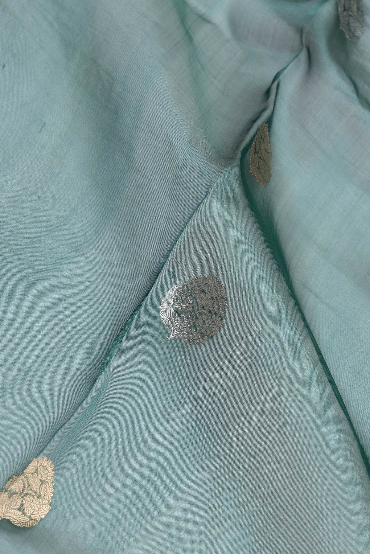Close up of Peacock Blue Dual Tone Organza Silk Saree with Zari Butta on the body and Zari Border.  displaying folds