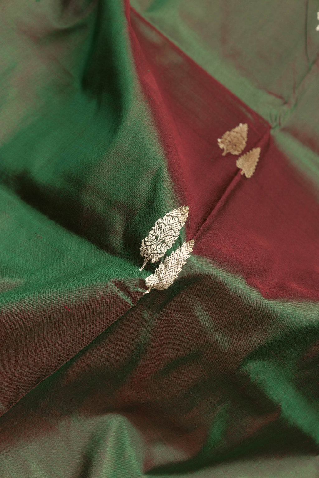 Close up of Green Dual Tone Banarasi Silk Saree with Thread Butta on the body and Thread Border.  displaying folds