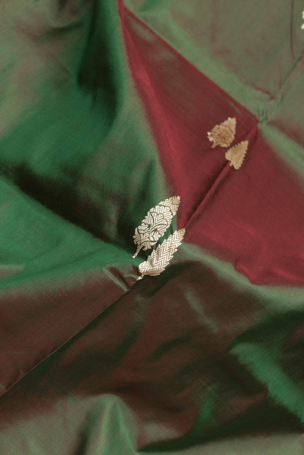 Close up of Green Dual Tone Banarasi Silk Saree with Thread Butta on the body and Thread Border.  displaying folds
