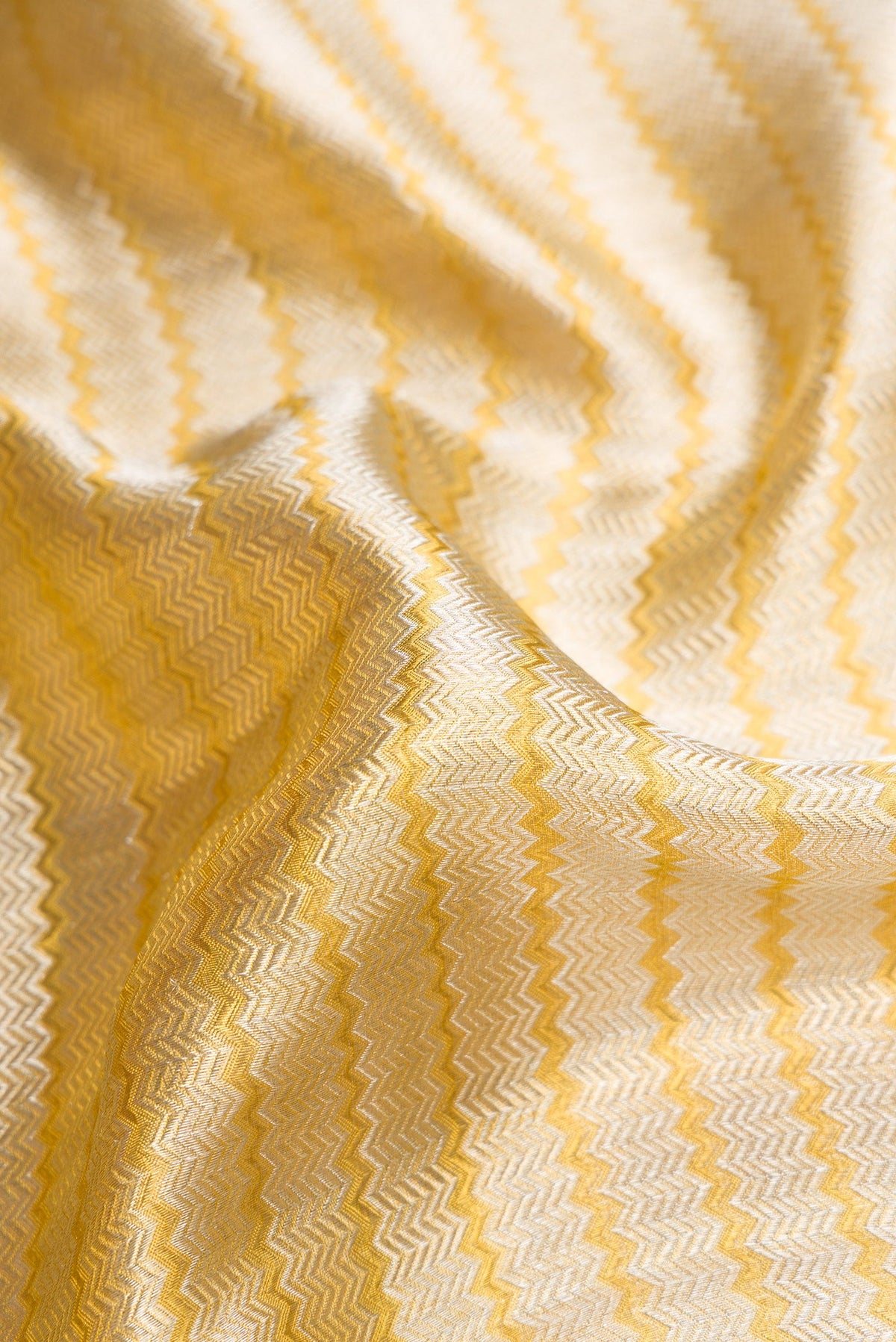 Close up of Silver Dual Tone Kanjivaram Tissue Silk Saree with Zari Brocade on the body and Zari Border.  displaying folds