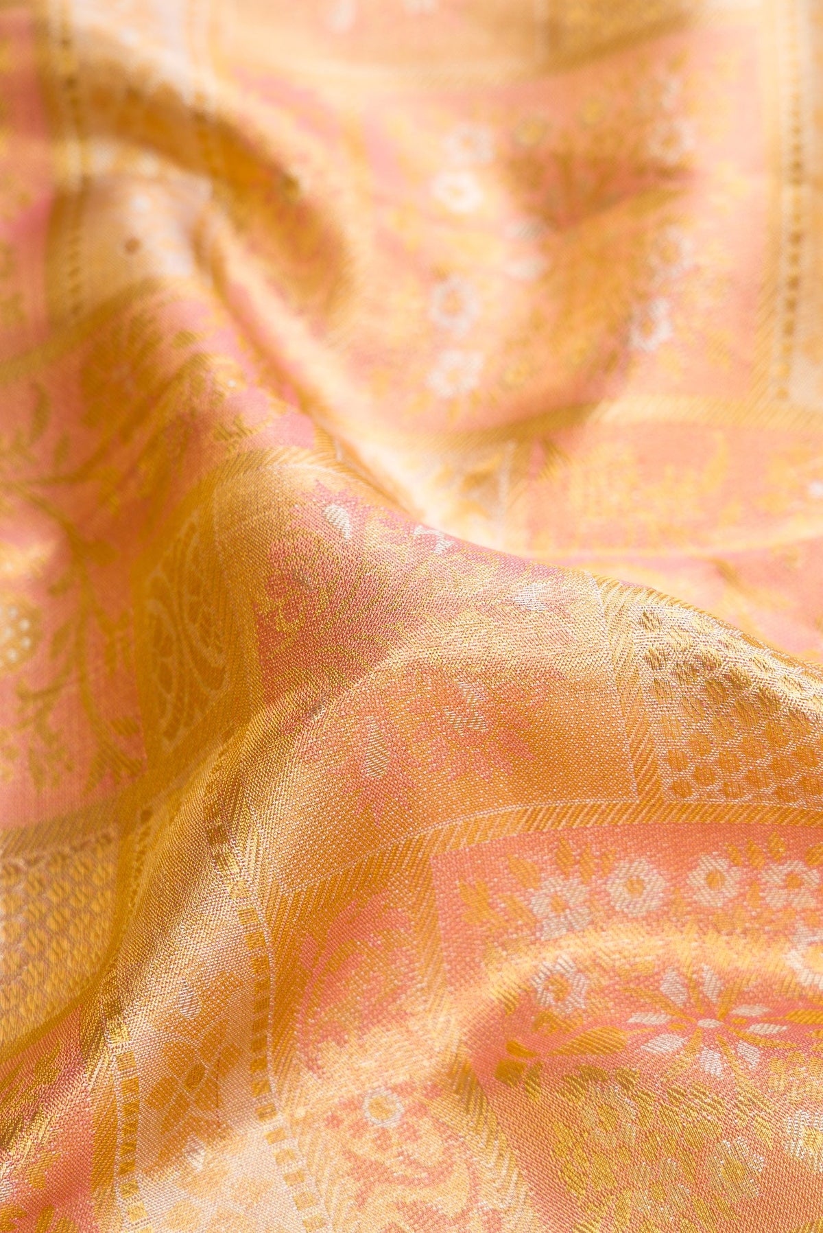Close up of Rose Gold Dual Tone Kanjivaram Tissue Silk Saree with Zari Brocade on the body and Zari Border.  displaying folds