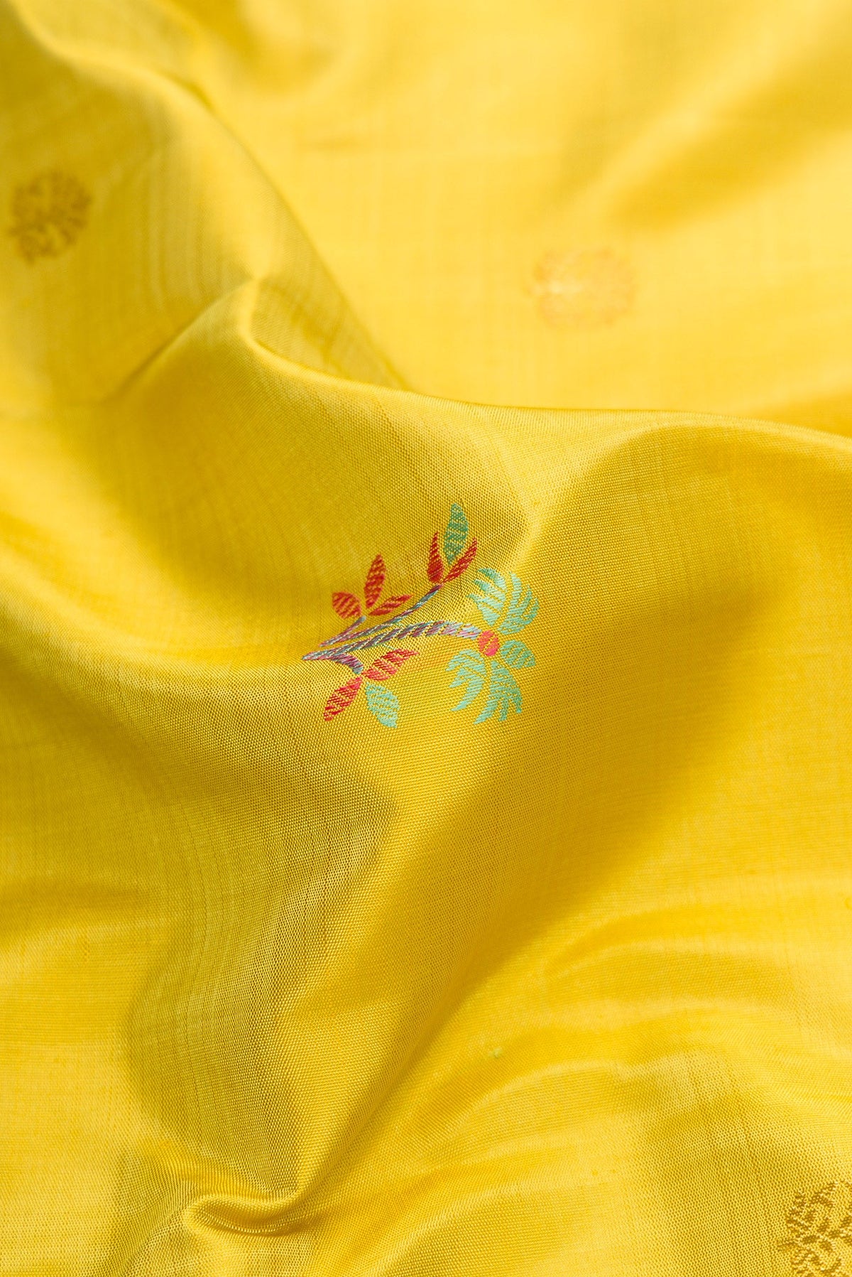 Close up of Pure Silk Pure Zari Lemon Yellow Dual Tone Kanchipuram Saree with Zari And Thread Butta on the body and Zari And Thread Border.  displaying folds