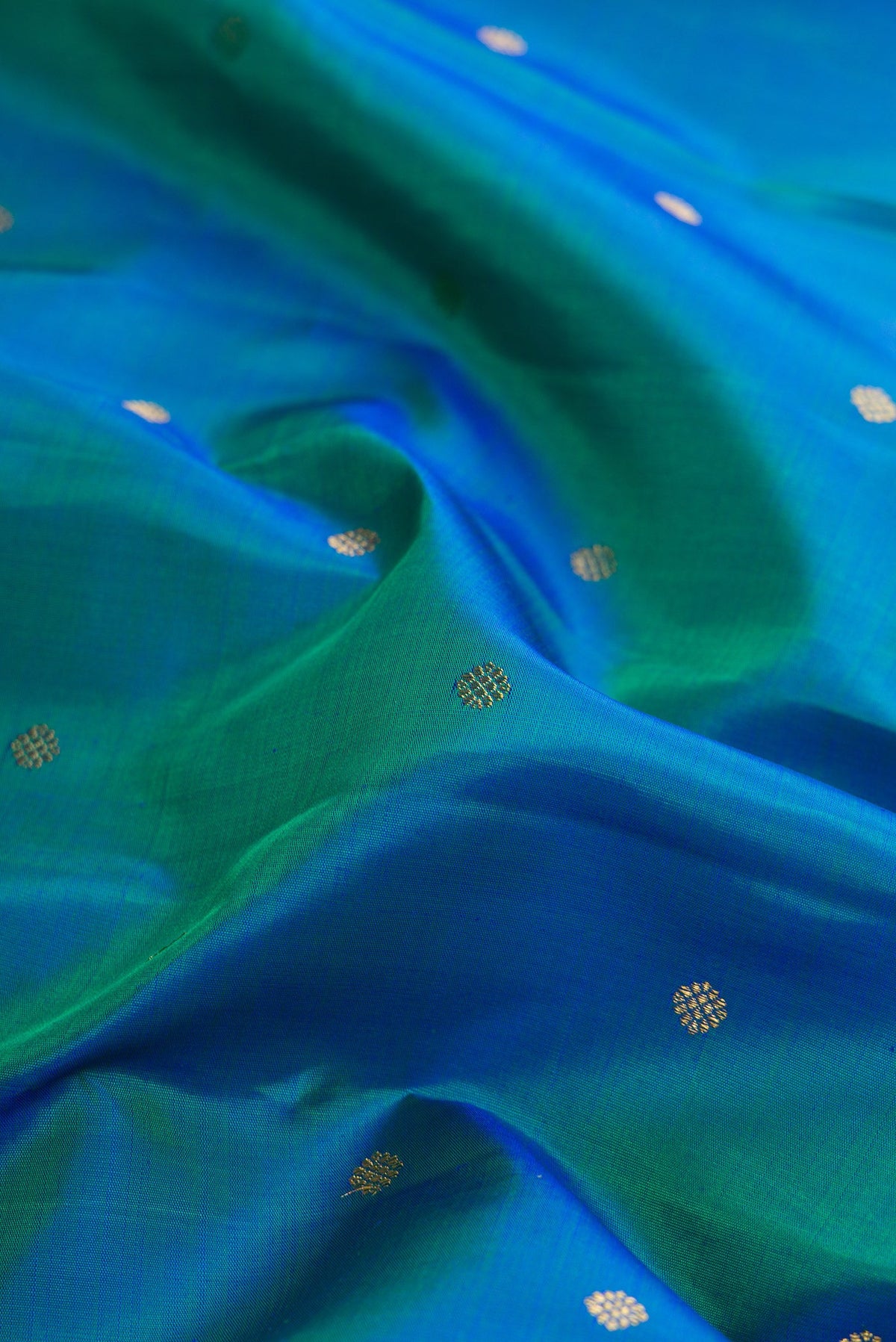 Close up of Pure Silk Pure Zari Peacock Blue Dual Tone Kanjivaram Saree with Zari Butta on the body and Zari Border.  displaying folds