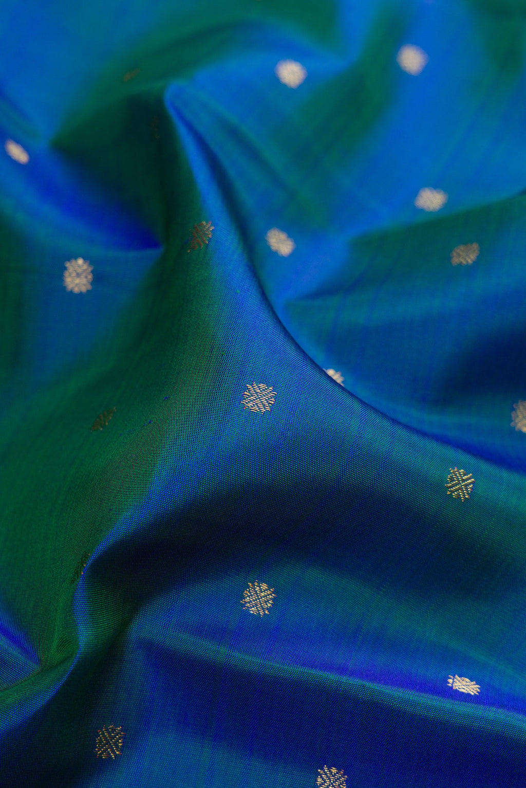 Close up of Pure Silk Pure Zari Peacock Blue Dual Tone Kanjivaram Saree with Zari Butta on the body and Zari Border.  displaying folds