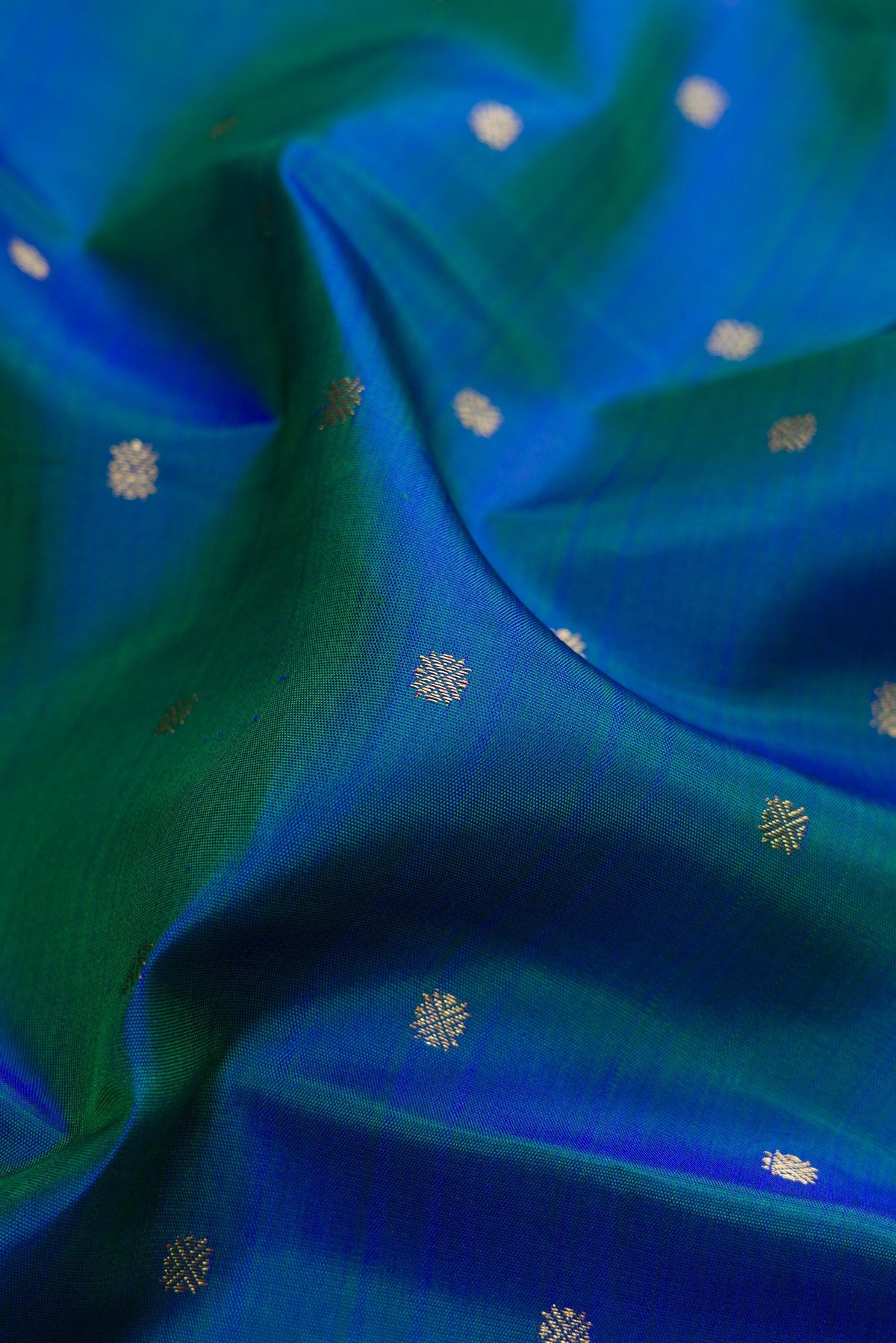 Close up of Pure Silk Pure Zari Peacock Blue Dual Tone Kanjivaram Saree with Zari Butta on the body and Zari Border.  displaying folds