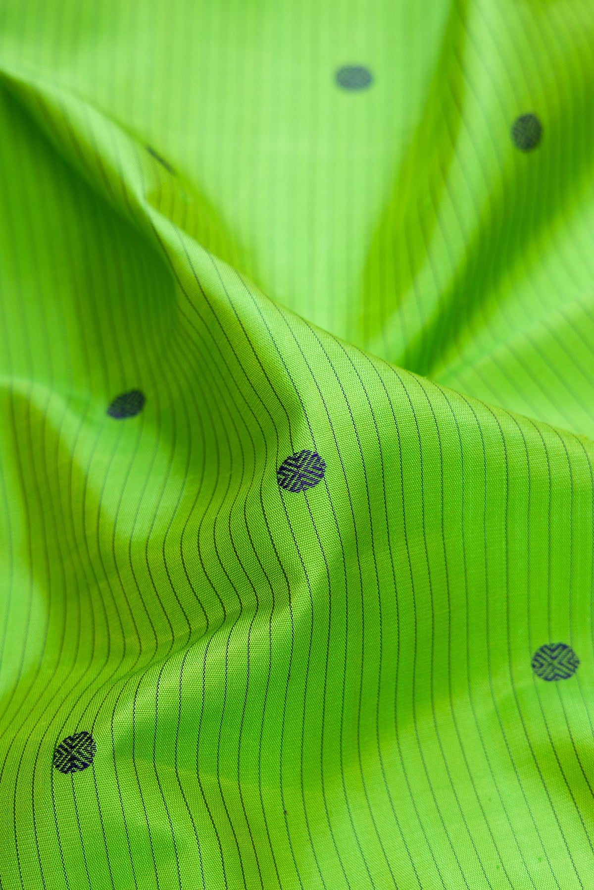 Close up of Pure Silk Pure Zari Parrot Green Dual Tone Kanjivaram Saree with Stripes on the body and Zari And Thread Border.  displaying folds