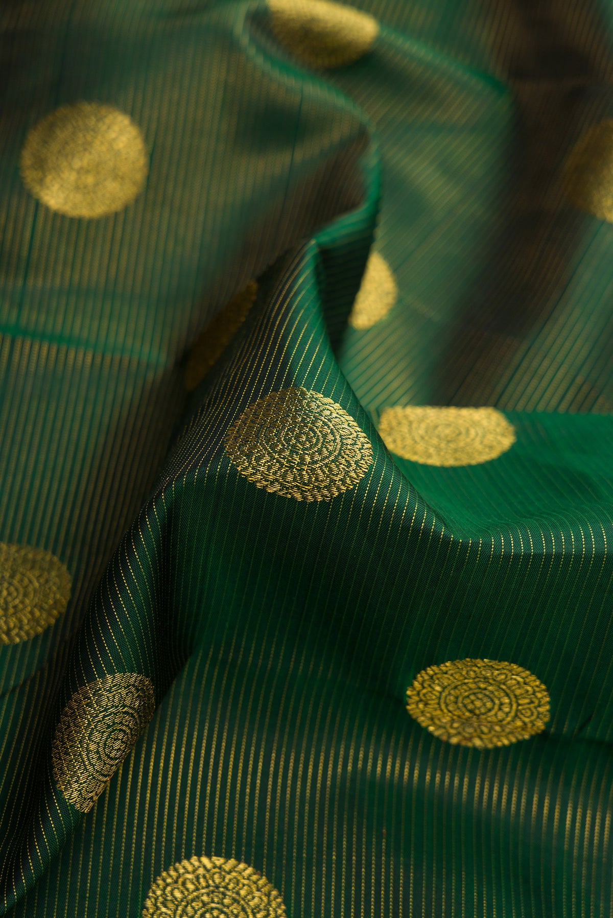 Close up of Bottle Green Kanchipuram Silk Saree with Zari Butta on the body and Zari Border.  displaying folds