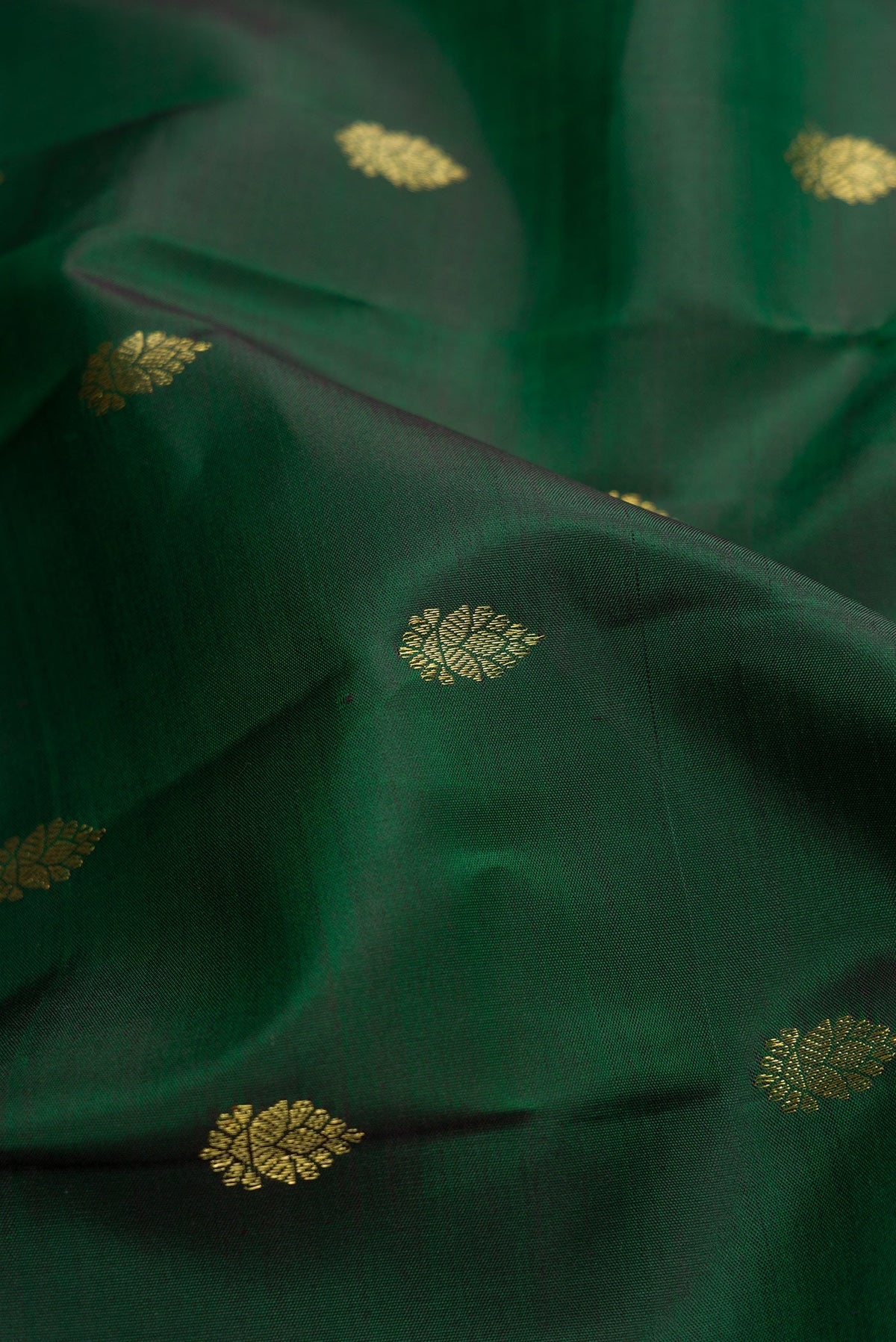Close up of Green Dual Tone Kanchipuram Silk Saree with Zari Butta on the body and Zari Border.  displaying folds