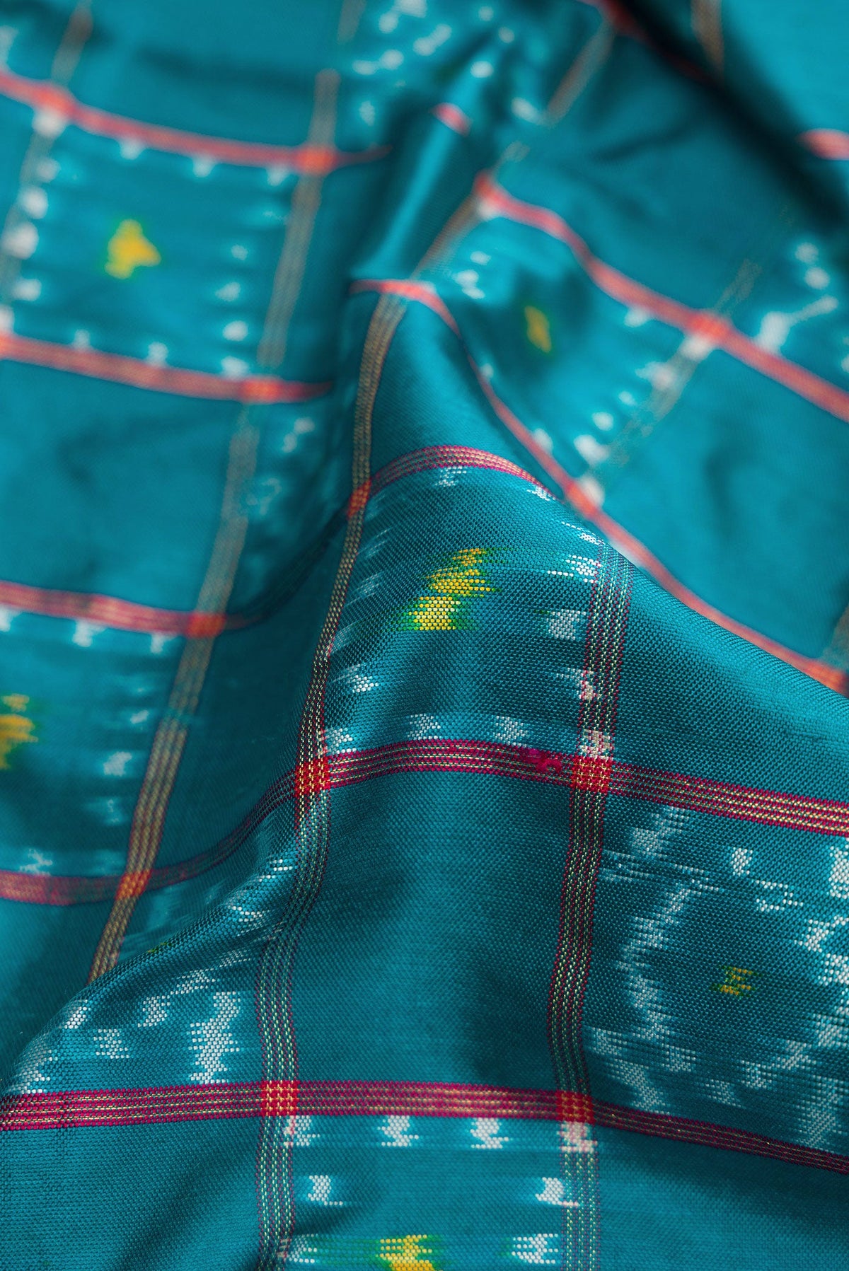Close up of Peacock Blue Dual Tone Double Ikat Saree with Ikat Print on the body and Ikat Border.  displaying folds