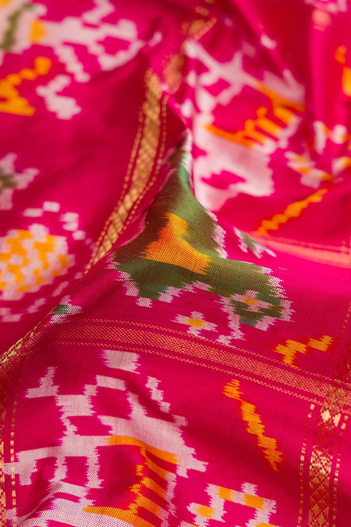 Close up of Pink Dual Tone Double Ikat Saree with Ikat Print on the body and Zari Border.  displaying folds