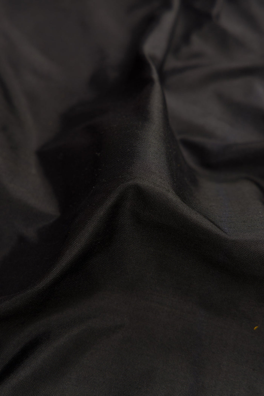 Close up of Black Dual Tone Double Ikat Saree with Plain Body and Zari Border.  displaying folds
