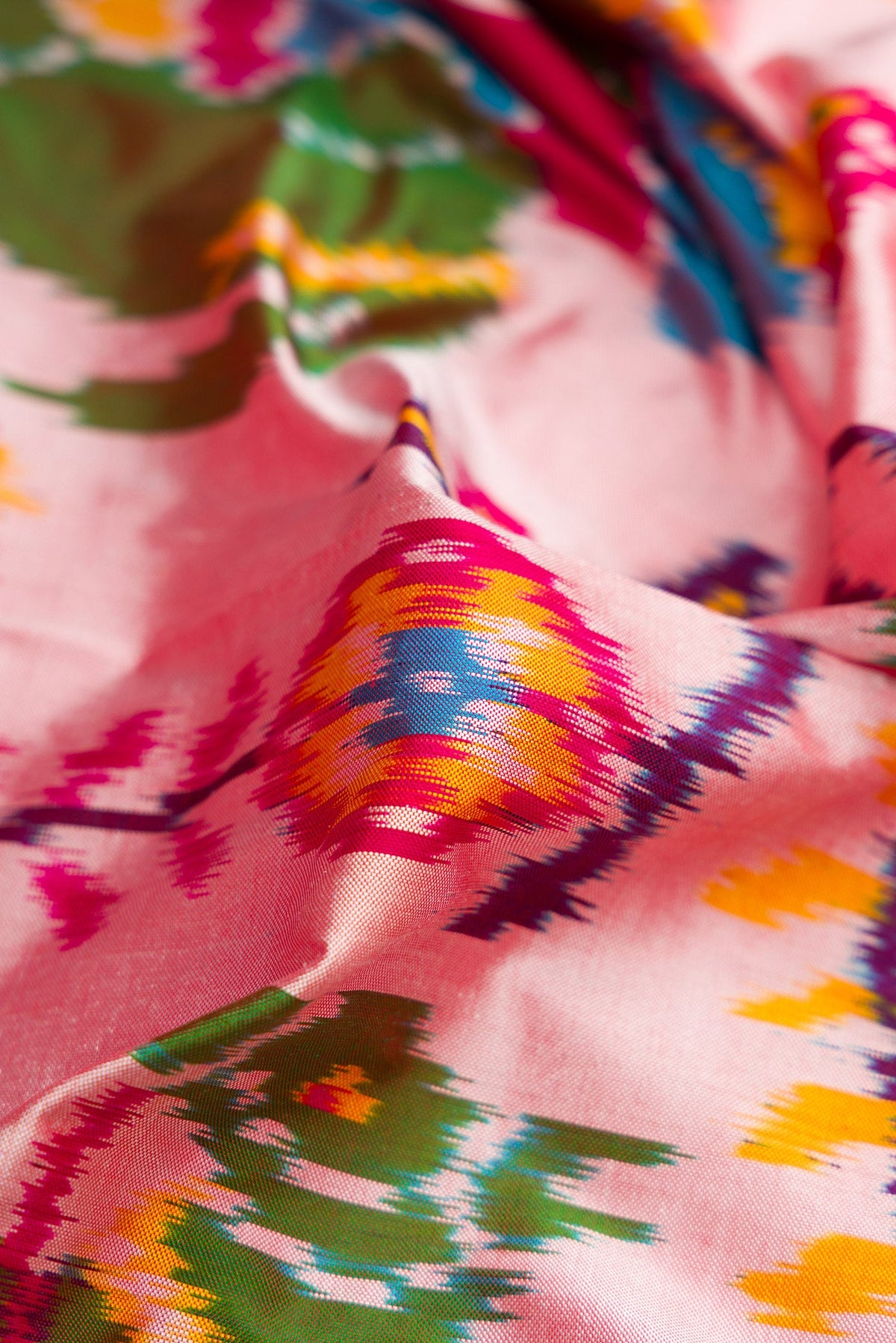 Close up of Pink Dual Tone Double Ikat Saree with Ikat Print on the body and Thread Border.  displaying folds