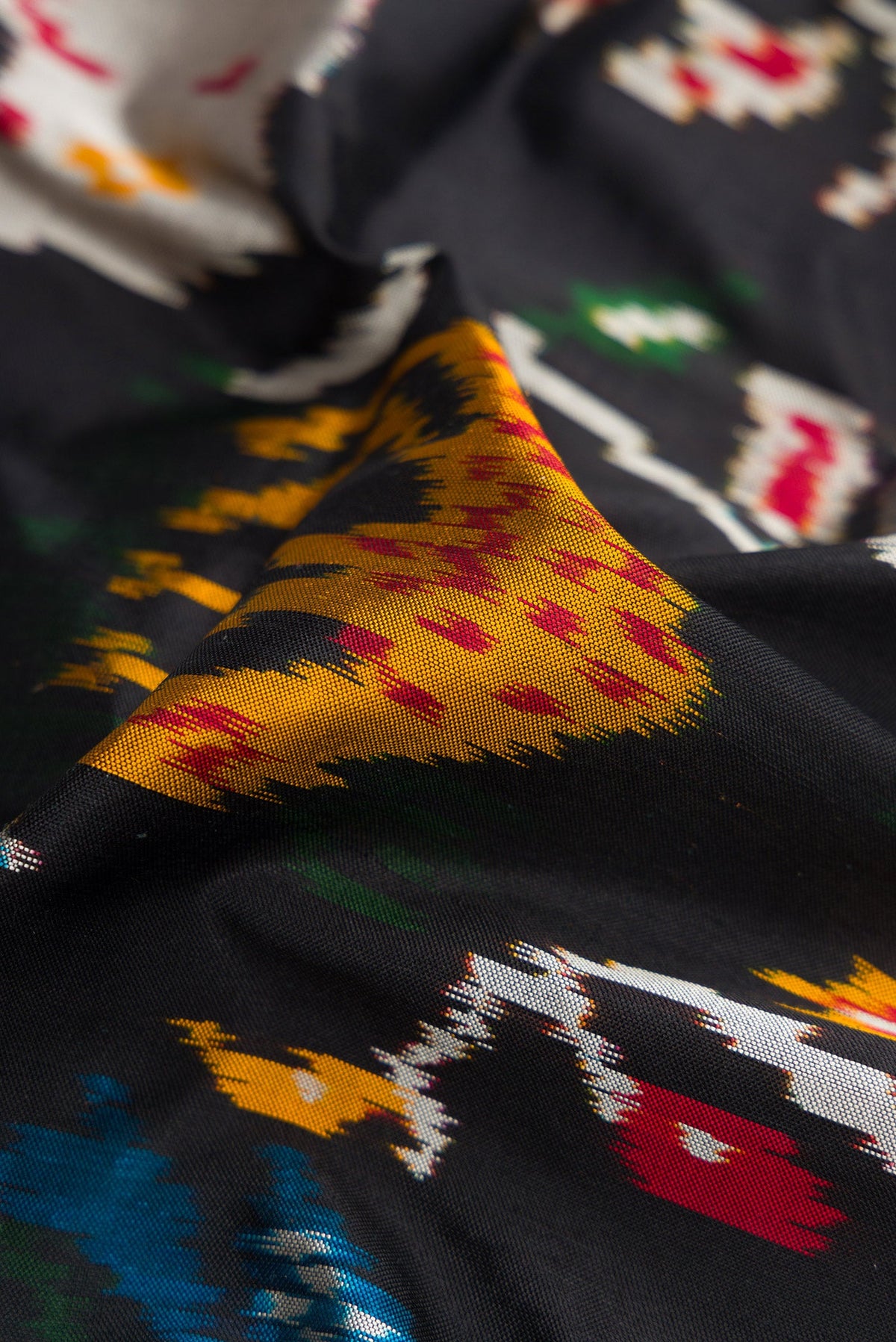 Close up of Black Dual Tone Double Ikat Saree with Ikat Print on the body and Thread Border.  displaying folds