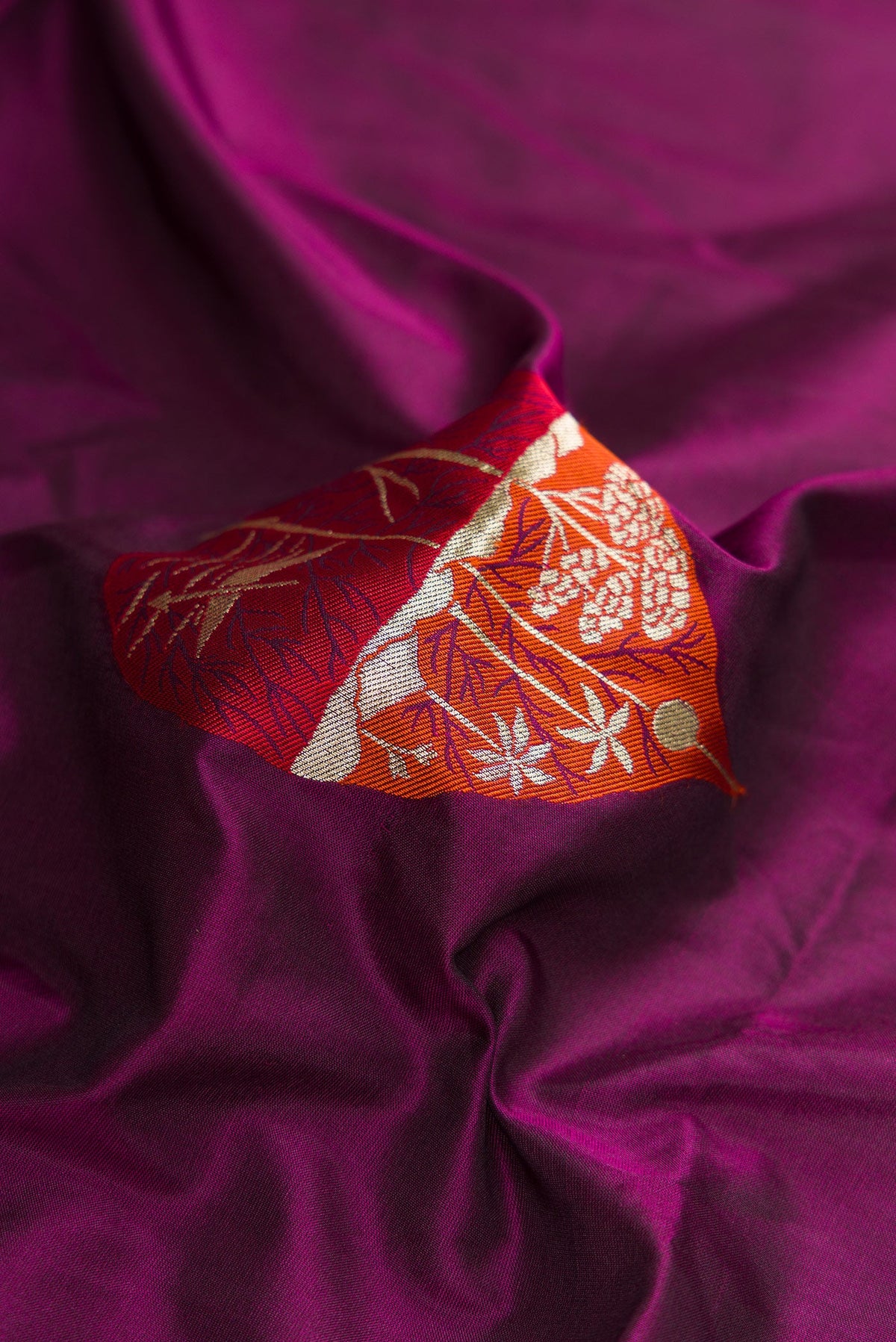 Close up of Burgundy Dual Tone Banarasi Silk Saree with Zari And Thread Butta on the body and Fancy Border.  displaying folds