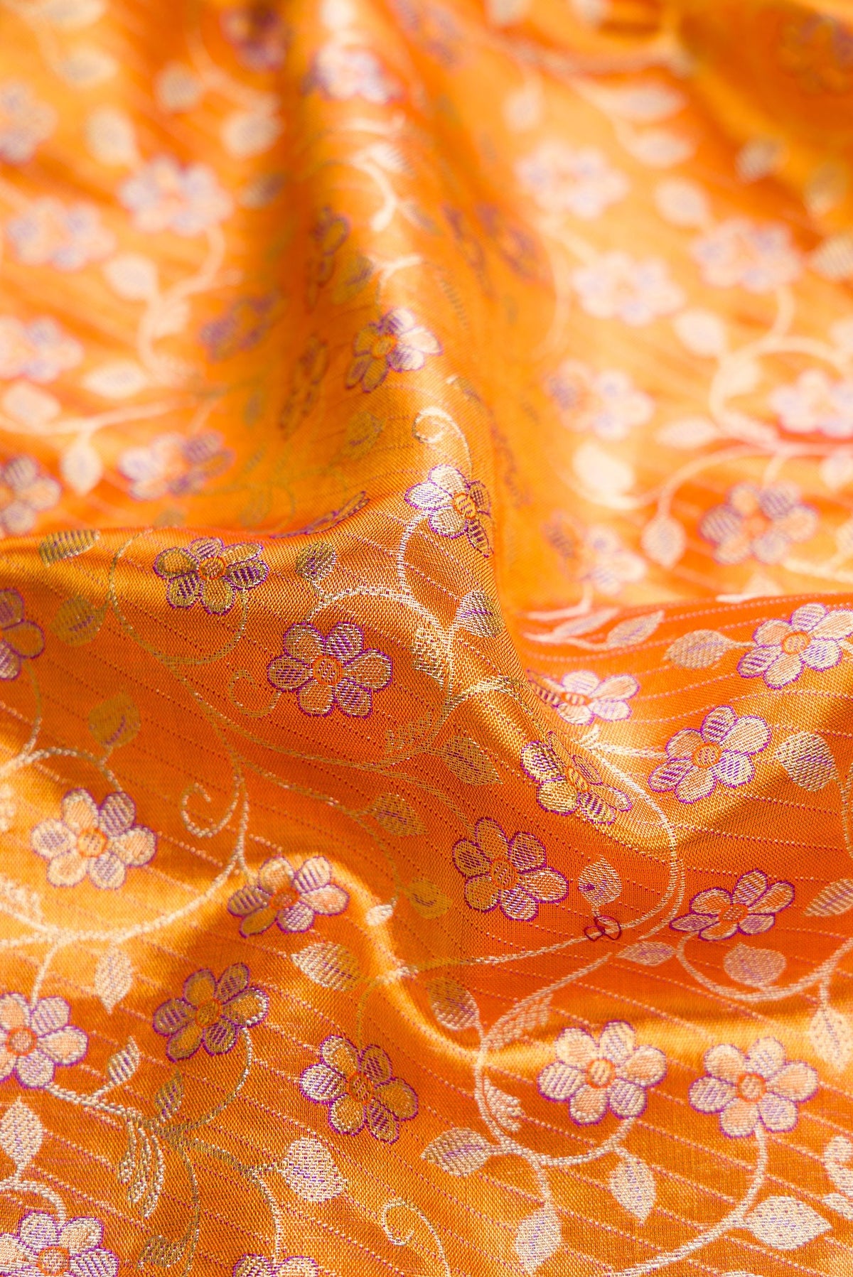 Close up of Golden Peach Dual Tone Kanjivaram Tissue Silk Saree with Zari Brocade on the body and Fancy Border.  displaying folds
