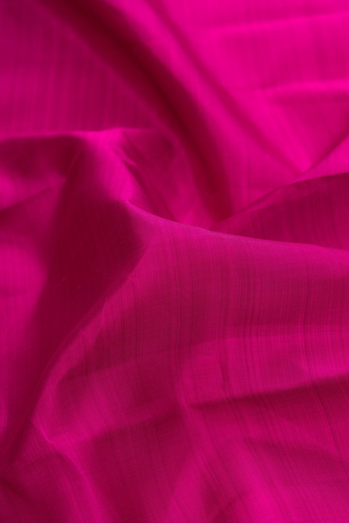 Close up of Magenta Dual Tone Kanjivaram Silk Saree with Plain Body and Zari Border.  displaying folds